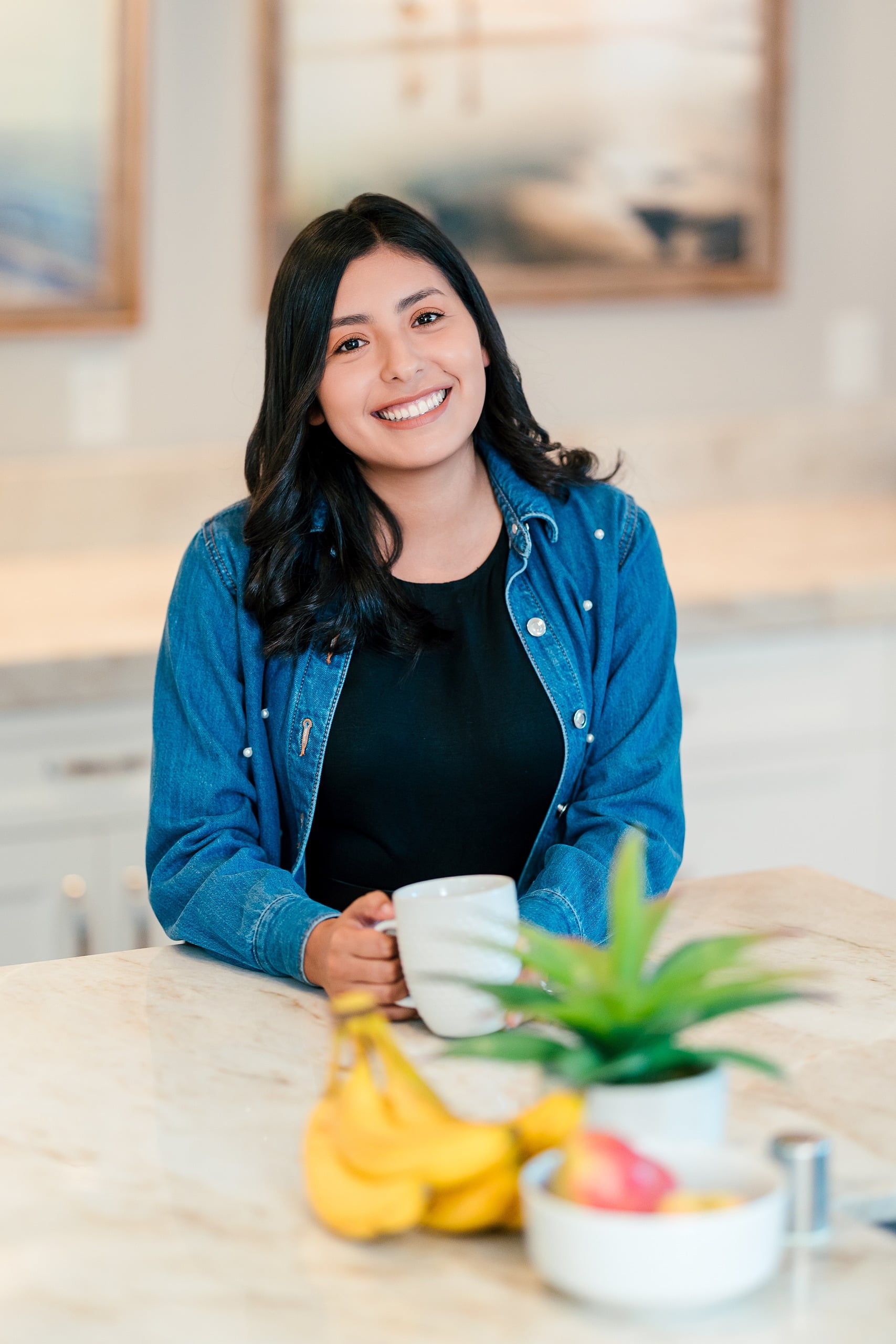 Capturing San Diego Spirit: Intention 2 Impact’s Team Retreat at Windansea — 17 Woman in denim jacket holding white mug at kitchen counter, golden light