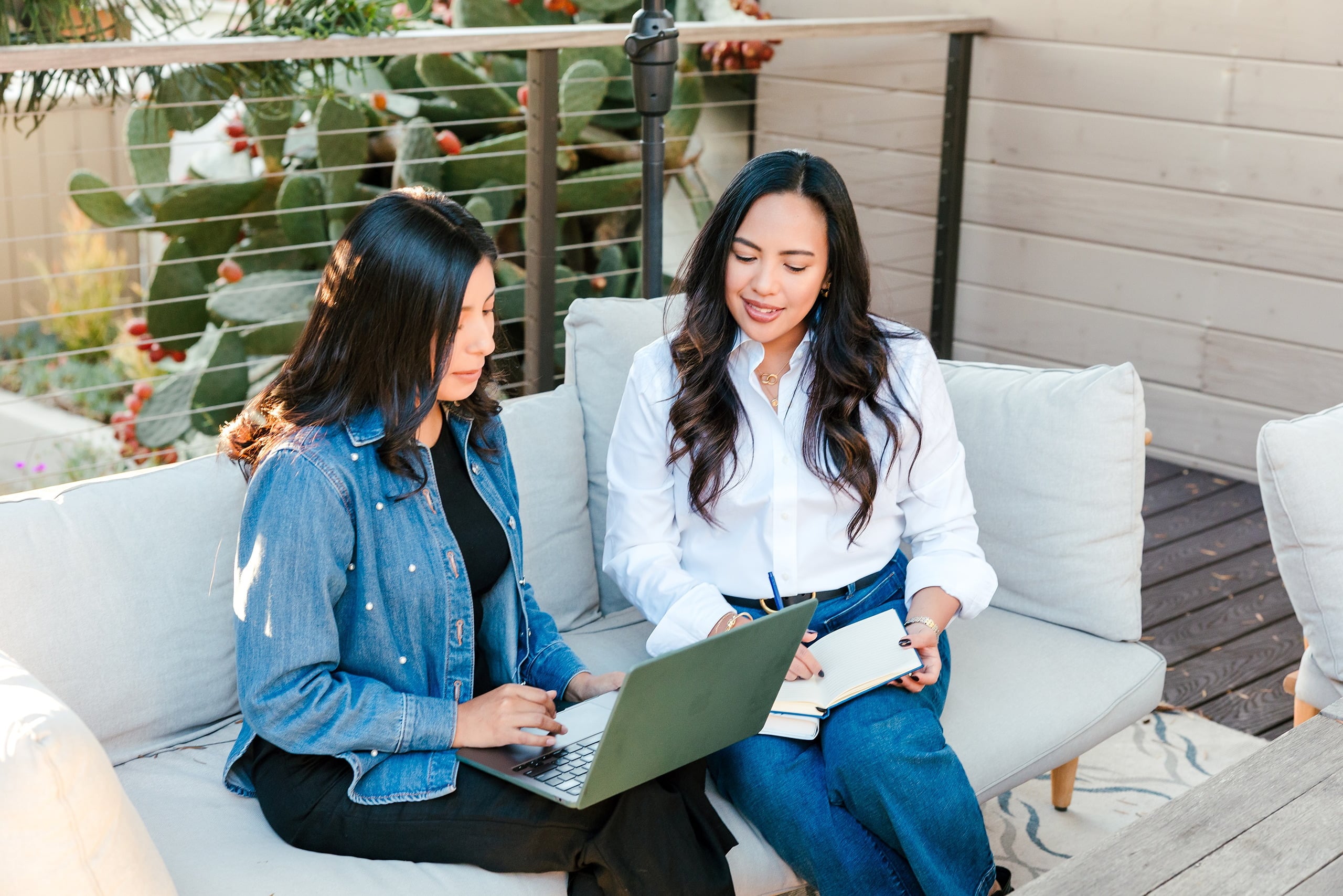 Capturing San Diego Spirit: Intention 2 Impact’s Team Retreat at Windansea — 21 Three women on outdoor lounge seating reviewing work at La Jolla