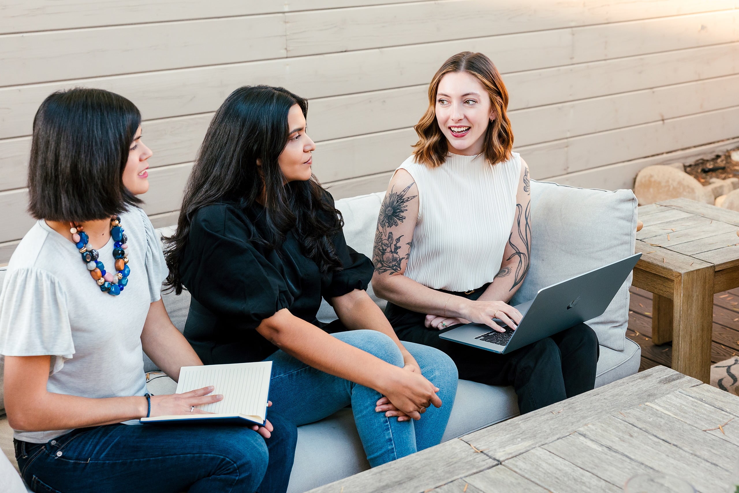 Capturing San Diego Spirit: Intention 2 Impact’s Team Retreat at Windansea — 22 Three team members on outdoor sofa reviewing laptop on deck