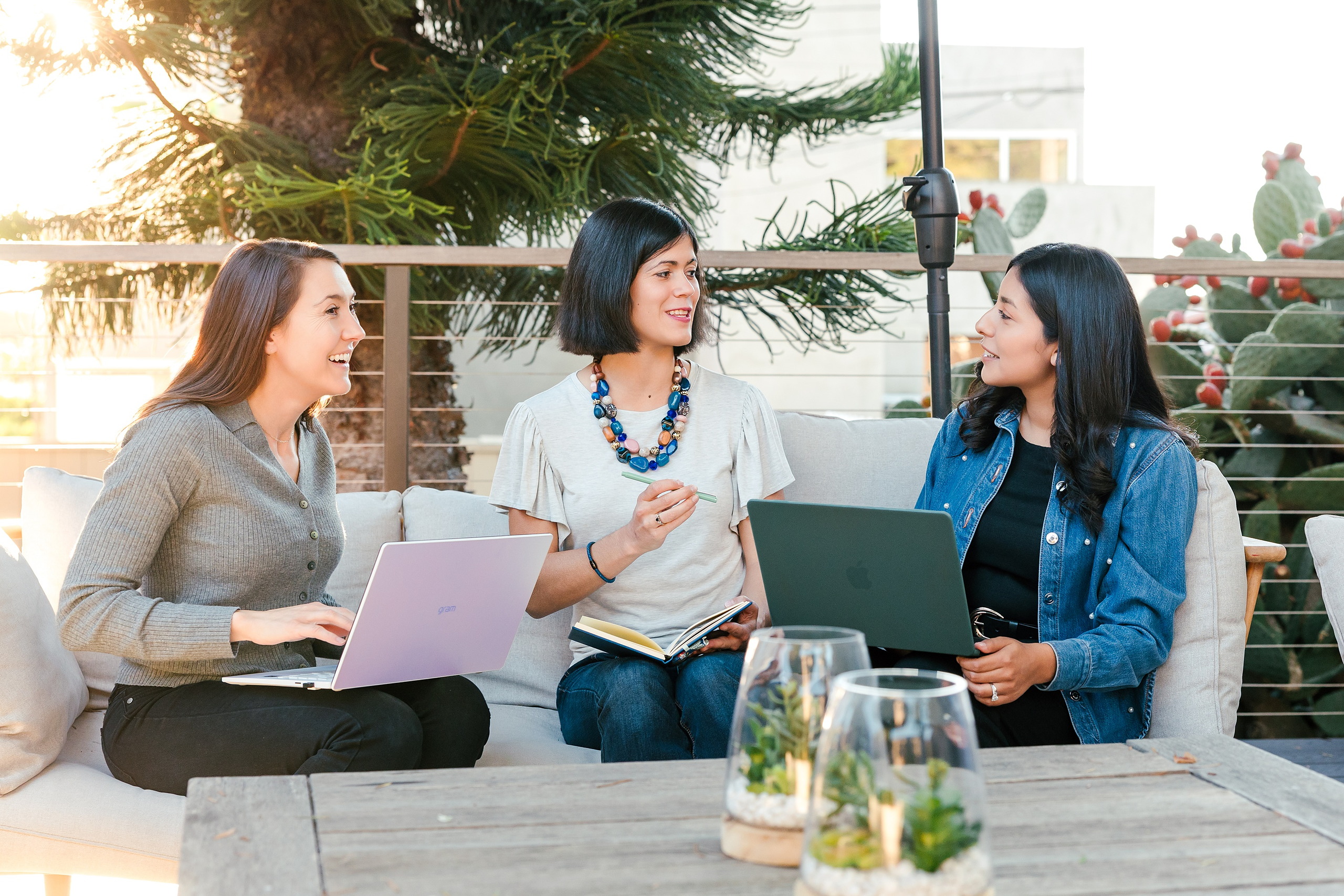 Capturing San Diego Spirit: Intention 2 Impact’s Team Retreat at Windansea — 23 Three women seated on outdoor lounge sofa with sea view behind