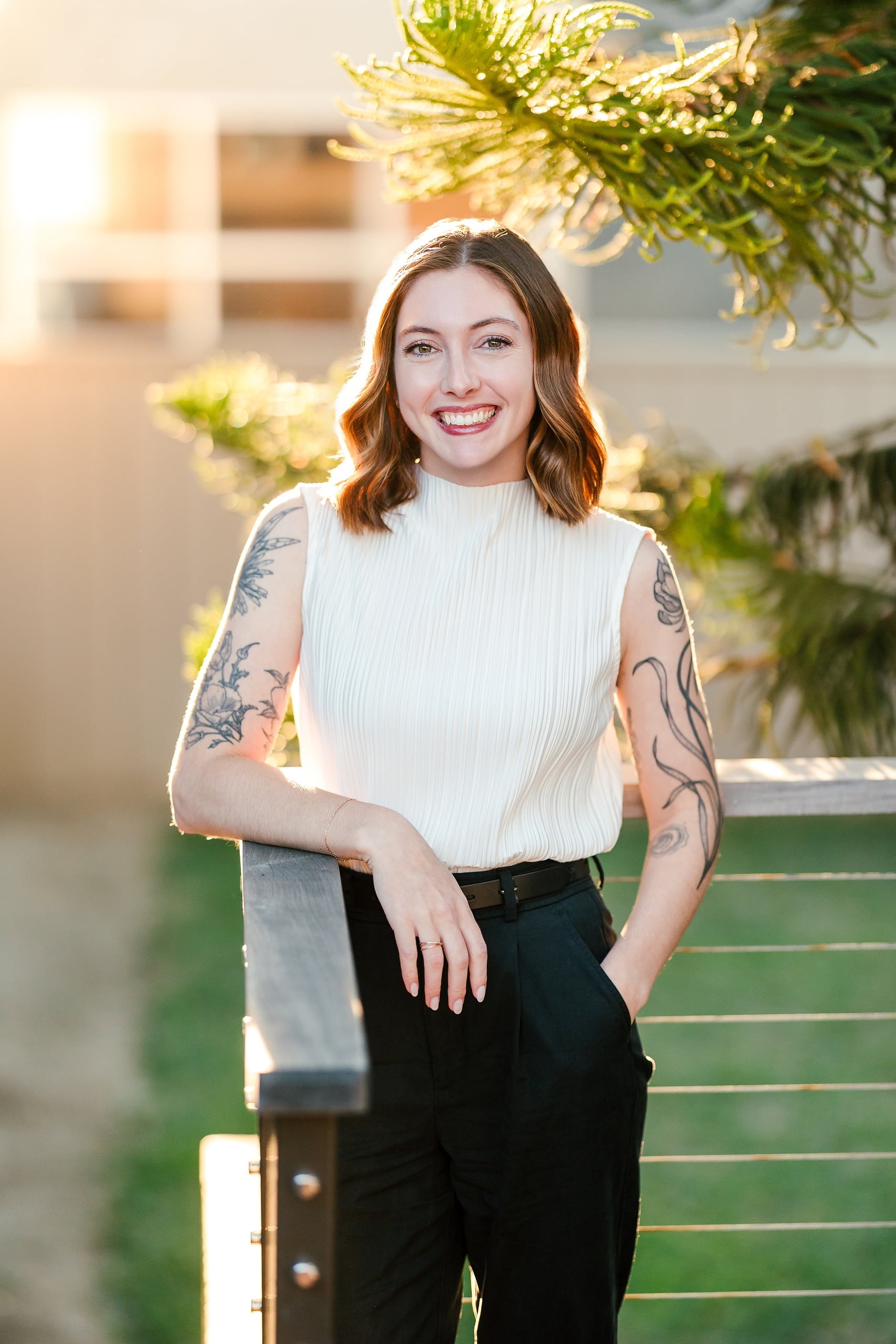 Capturing San Diego Spirit: Intention 2 Impact’s Team Retreat at Windansea — 27 Tattooed woman in white tank top standing on deck in sunset light