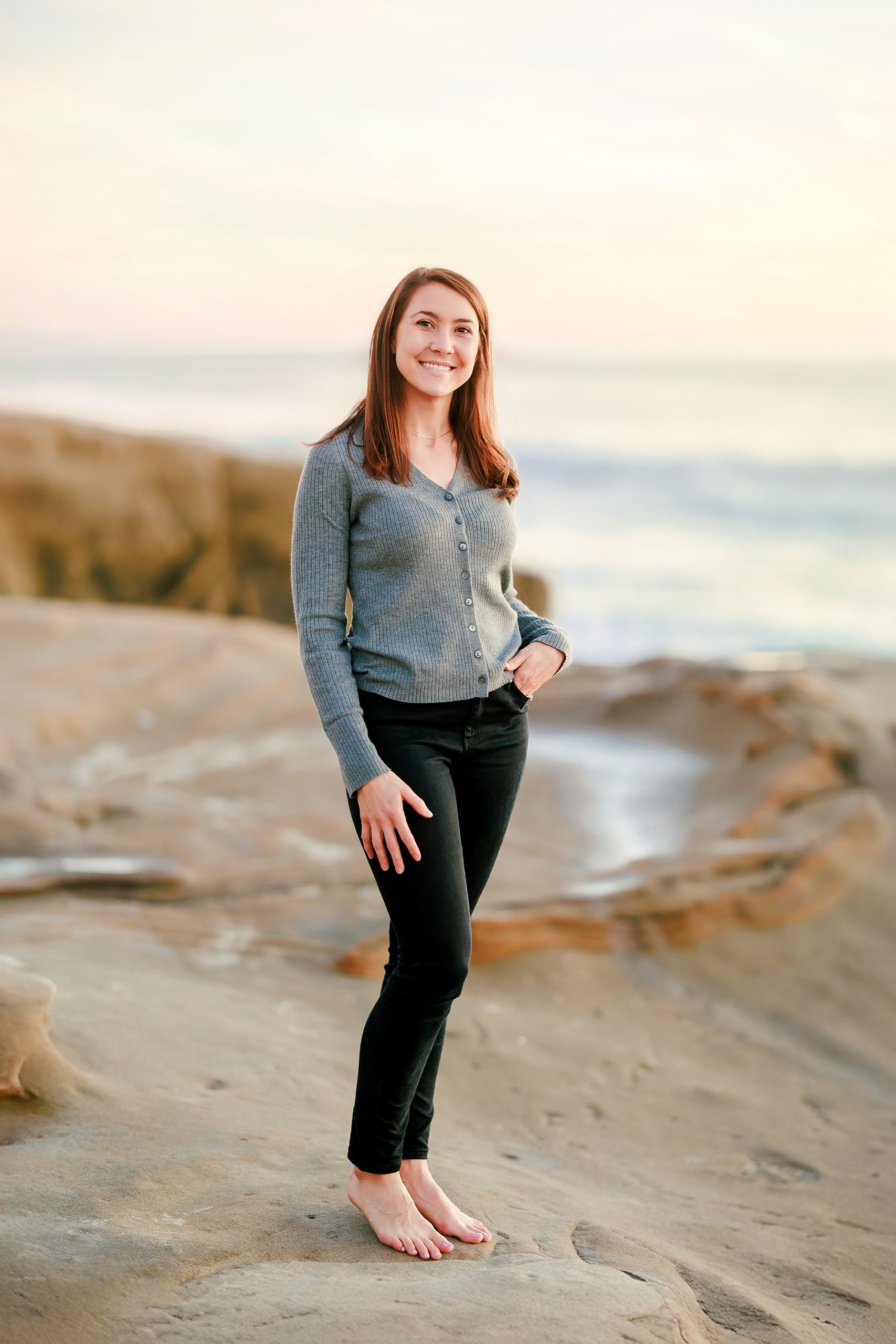Capturing San Diego Spirit: Intention 2 Impact’s Team Retreat at Windansea — 37 Woman in light cardigan standing barefoot on Windansea beach golden hour