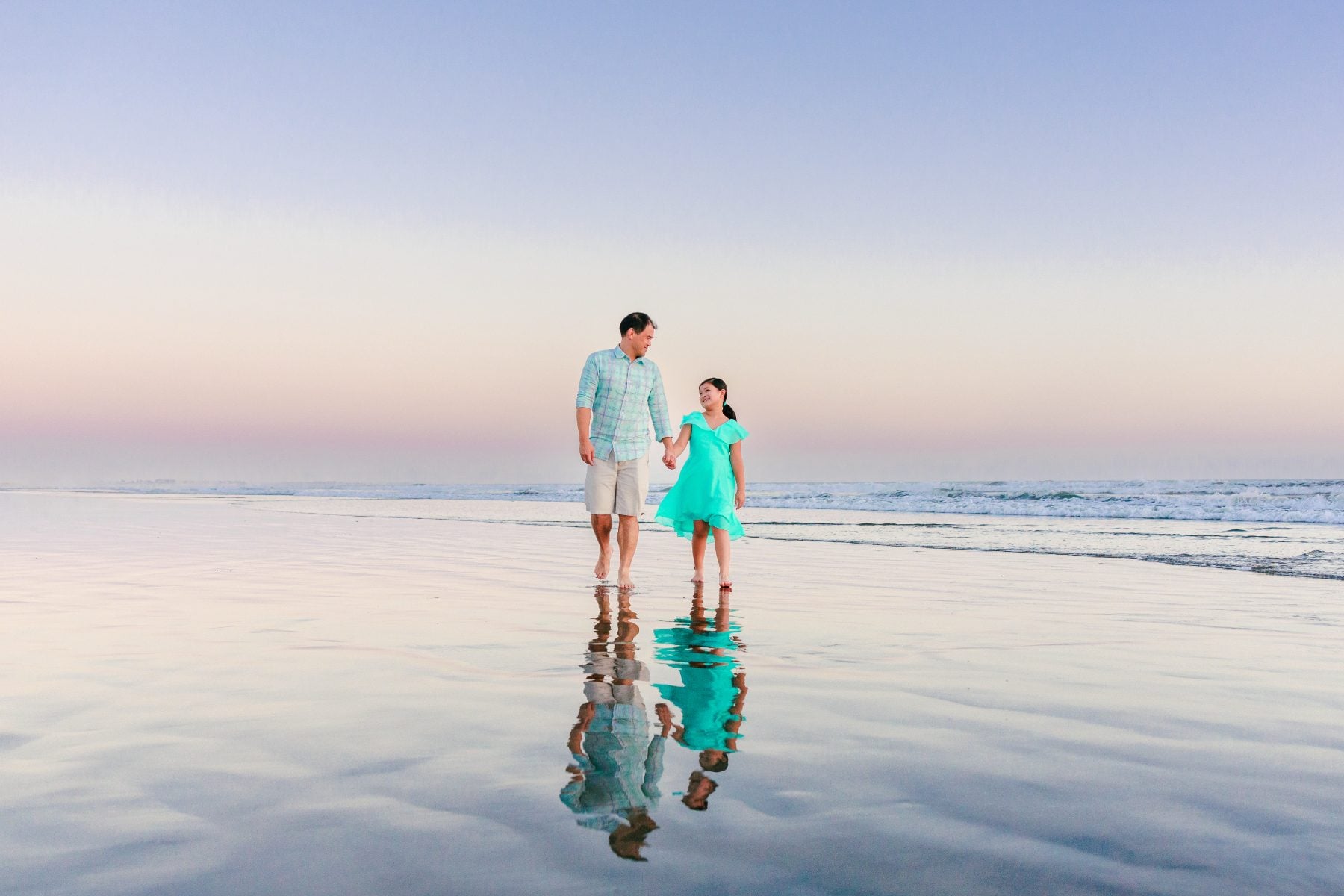 Father and daughter holding hands walking on reflective wet sand, Coronado Beach family photos