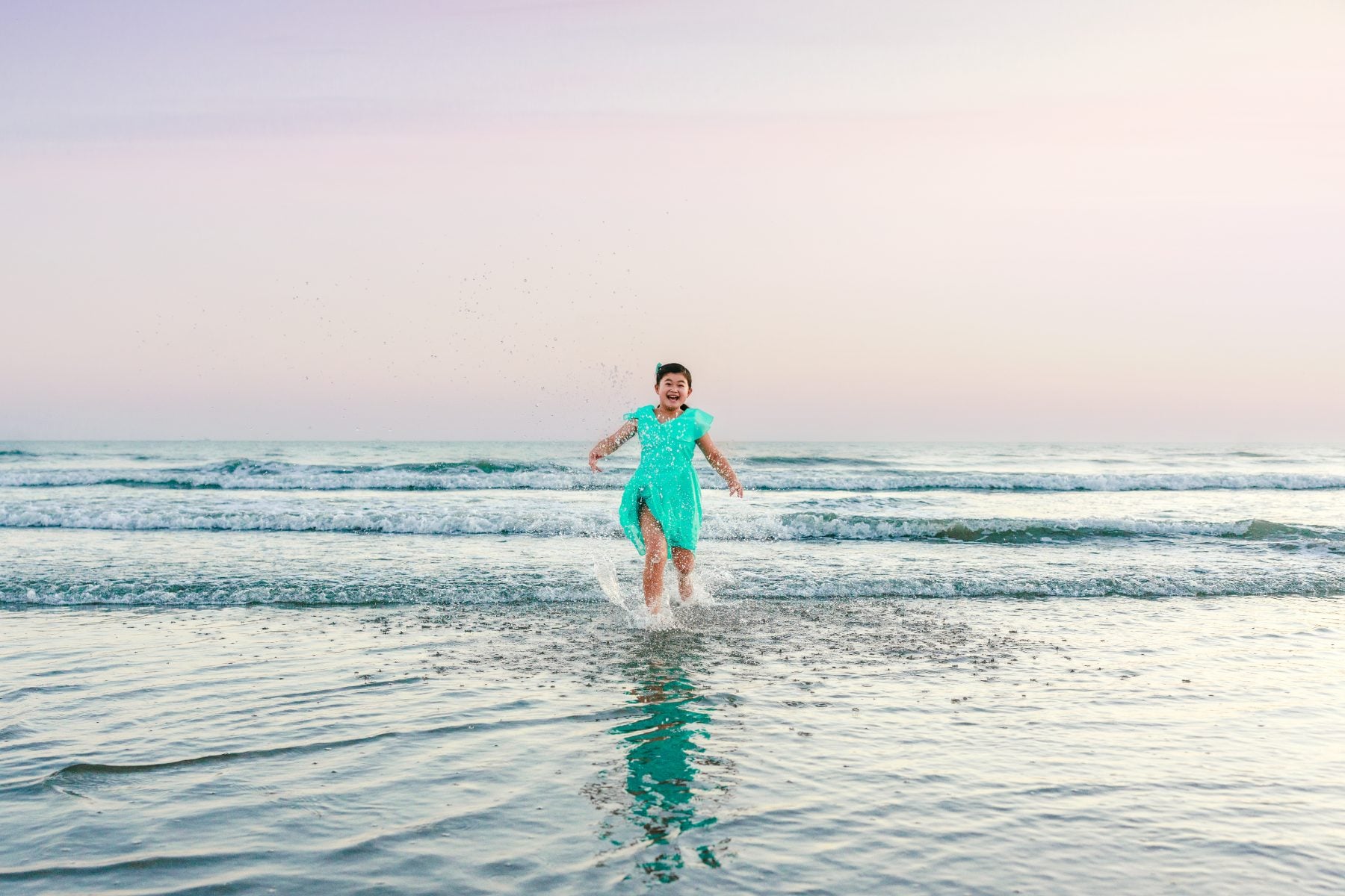 Girl splashing through shallow surf running along Coronado Beach shoreline