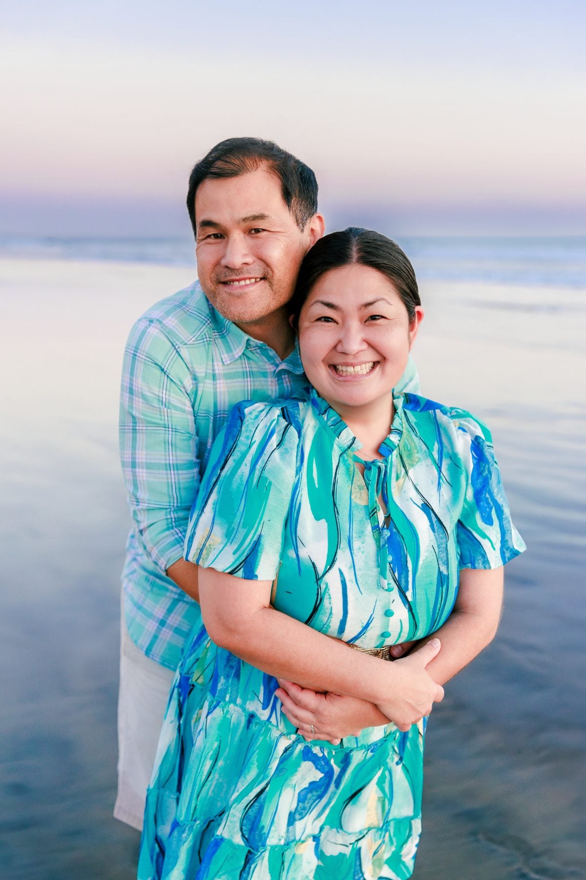 Husband embracing wife on the shoreline at Coronado Beach sunset