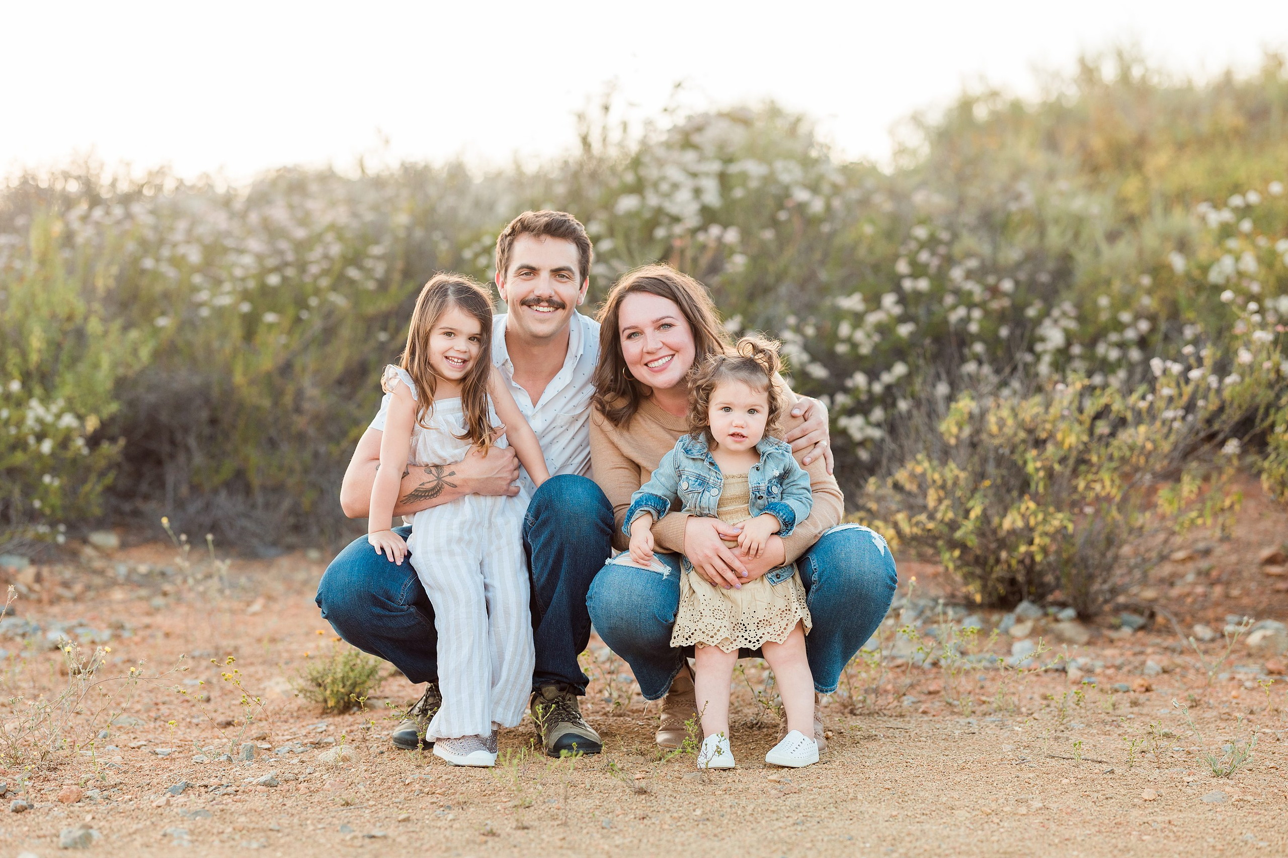 Dictionary Hill Nature Trails Family Photography in San Diego — 03 Family of four crouching on sandy ground at Dictionary Hill trails