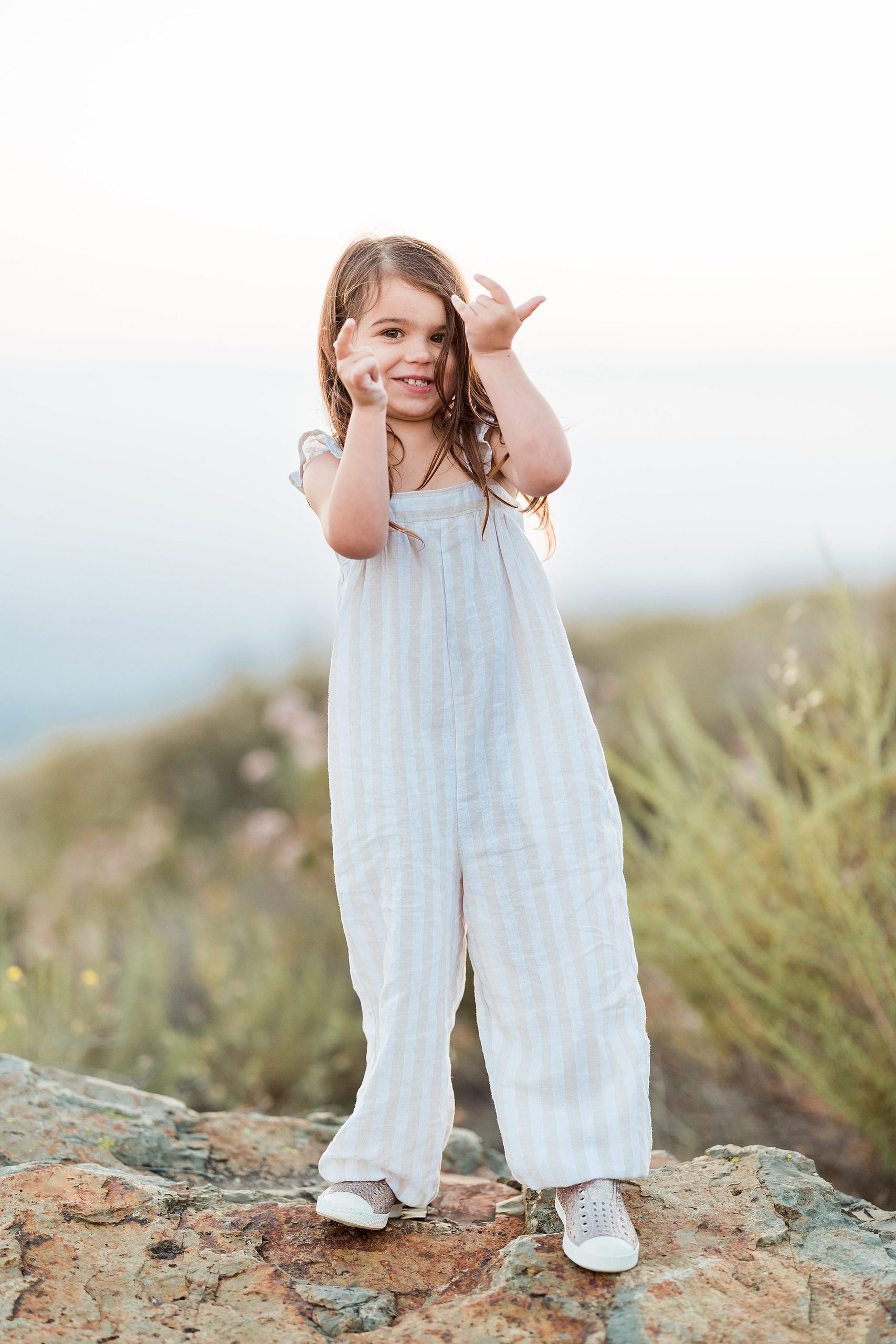 Dictionary Hill Nature Trails Family Photography in San Diego — 23 Older child posing with raised arms on high rock at Dictionary Hill