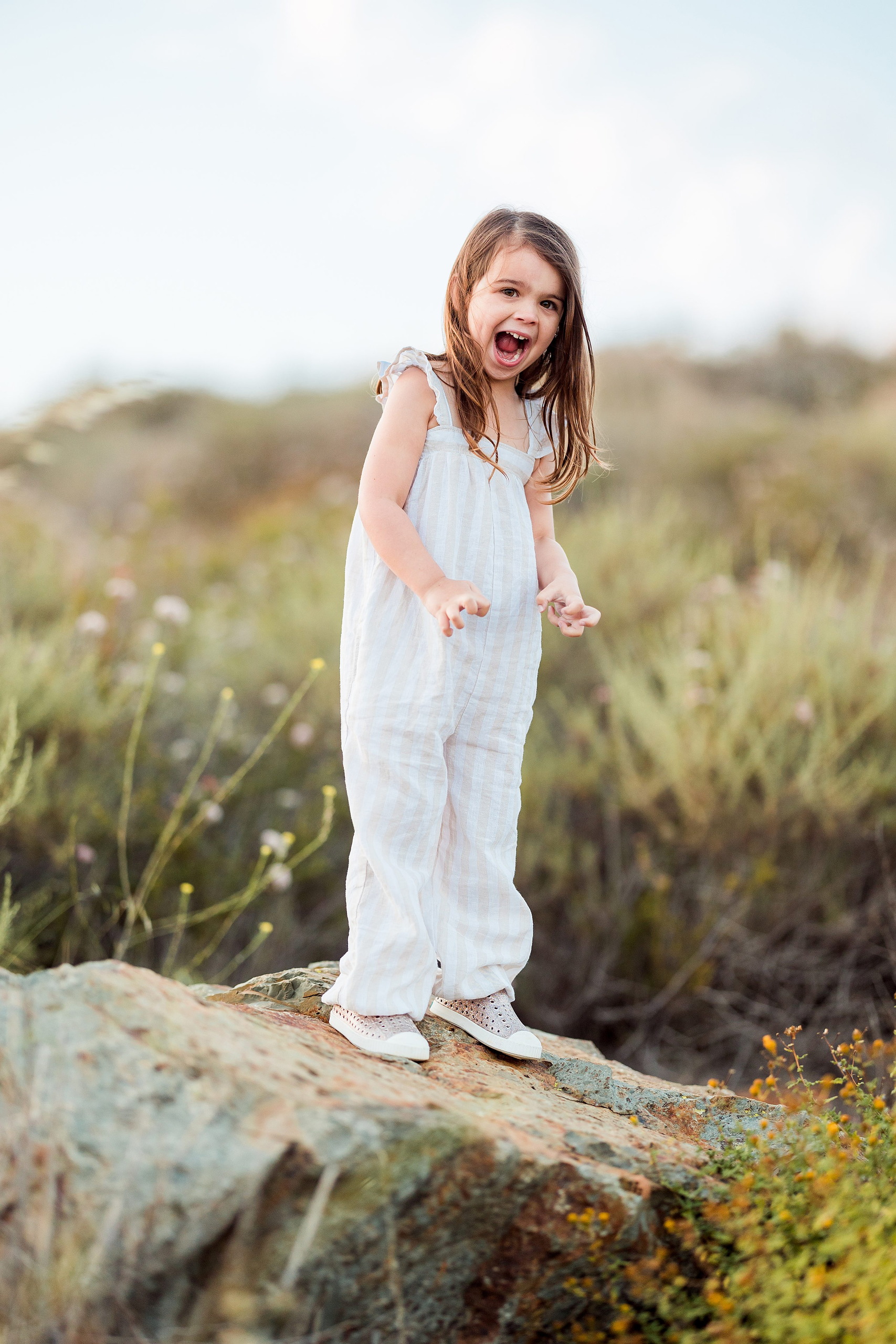 Dictionary Hill Nature Trails Family Photography in San Diego — 25 Child standing with arms raised celebrating on Dictionary Hill rock