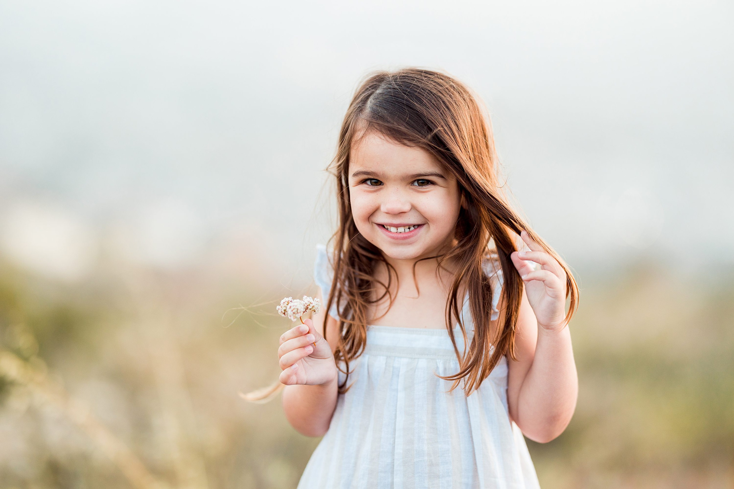 Dictionary Hill Nature Trails Family Photography in San Diego — 28 Child holding delicate white flower among shrubs at Dictionary Hill