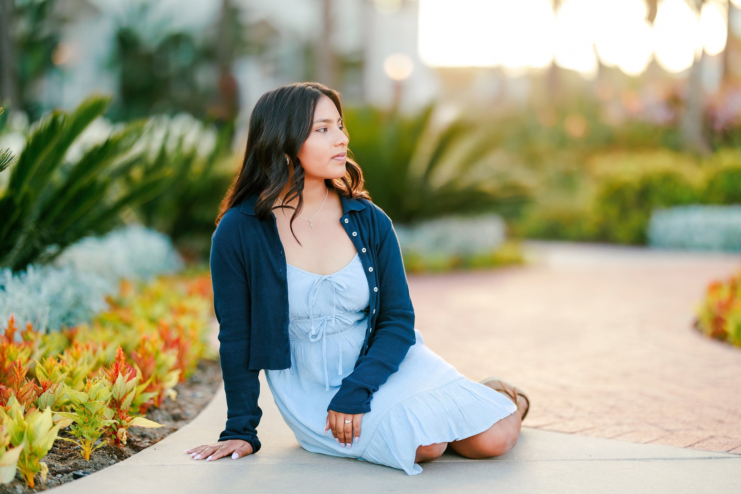 Evanna, Atalia, and Erleen’s Senior Session on Coronado — 06 Senior in gray crop top and jeans among flowering plants at Coronado