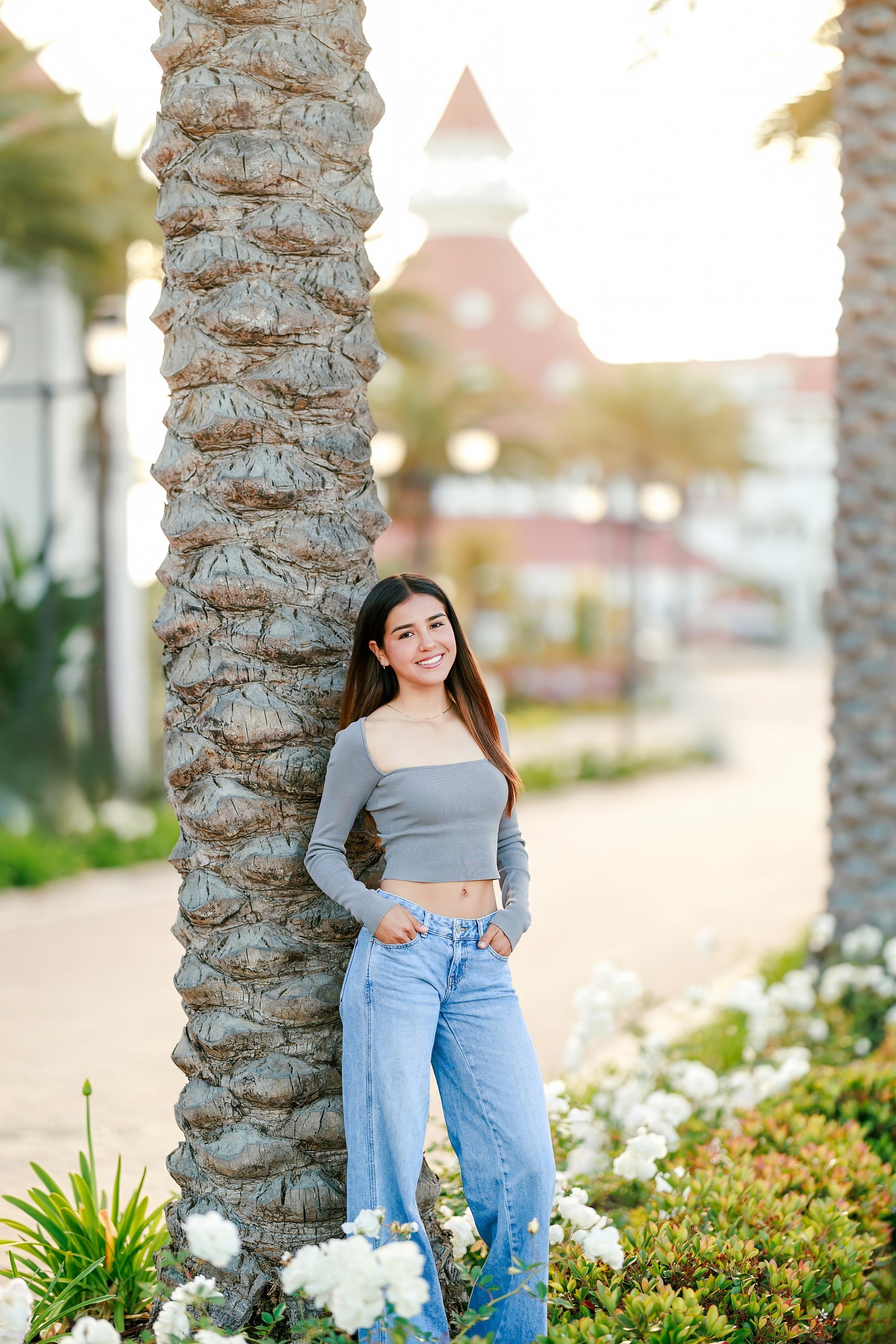 Evanna, Atalia, and Erleen’s Senior Session on Coronado — 08 Senior in light blue dress smiling near colorful flowers at Coronado