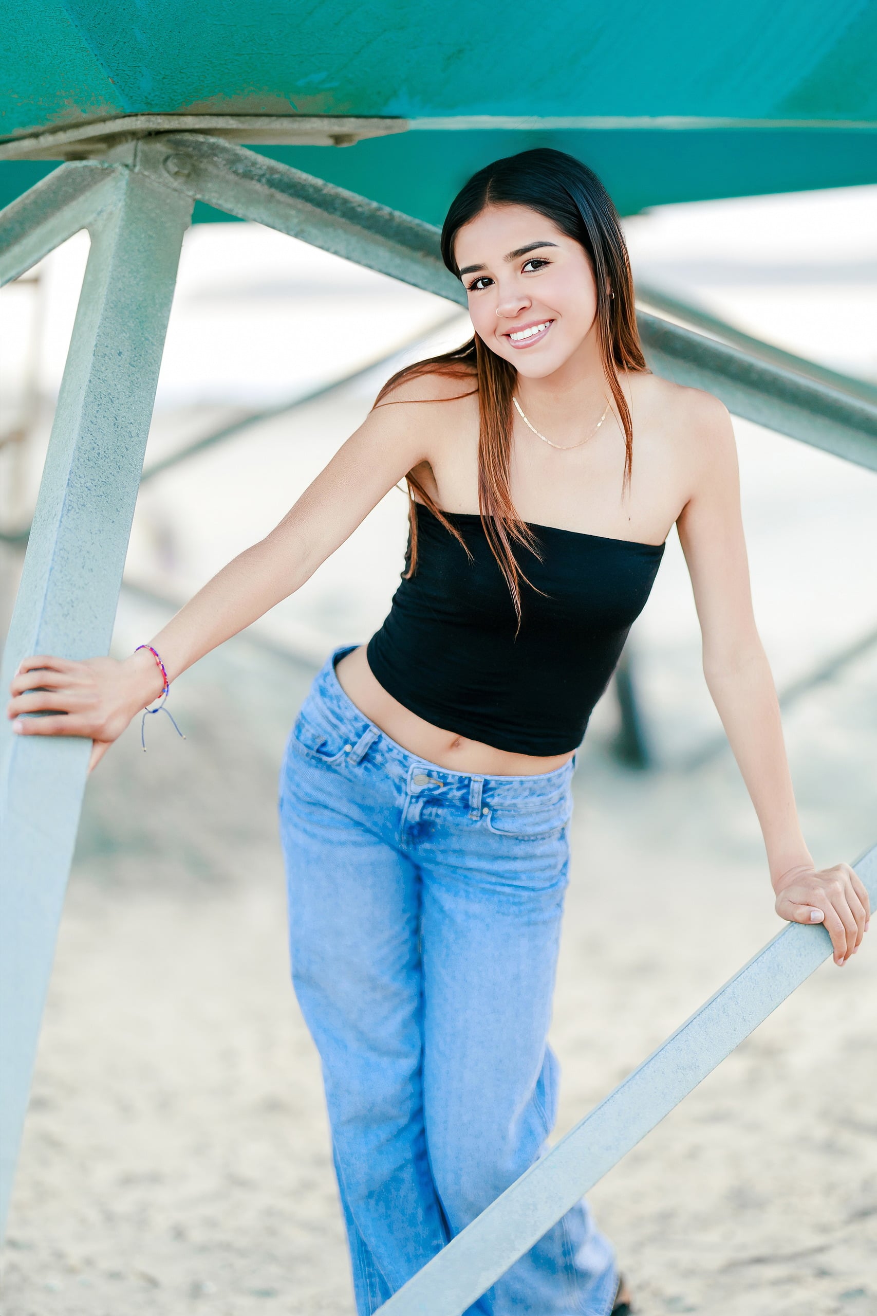 Evanna, Atalia, and Erleen’s Senior Session on Coronado — 16 Senior in black crop top smiling on pier structure at Coronado shore
