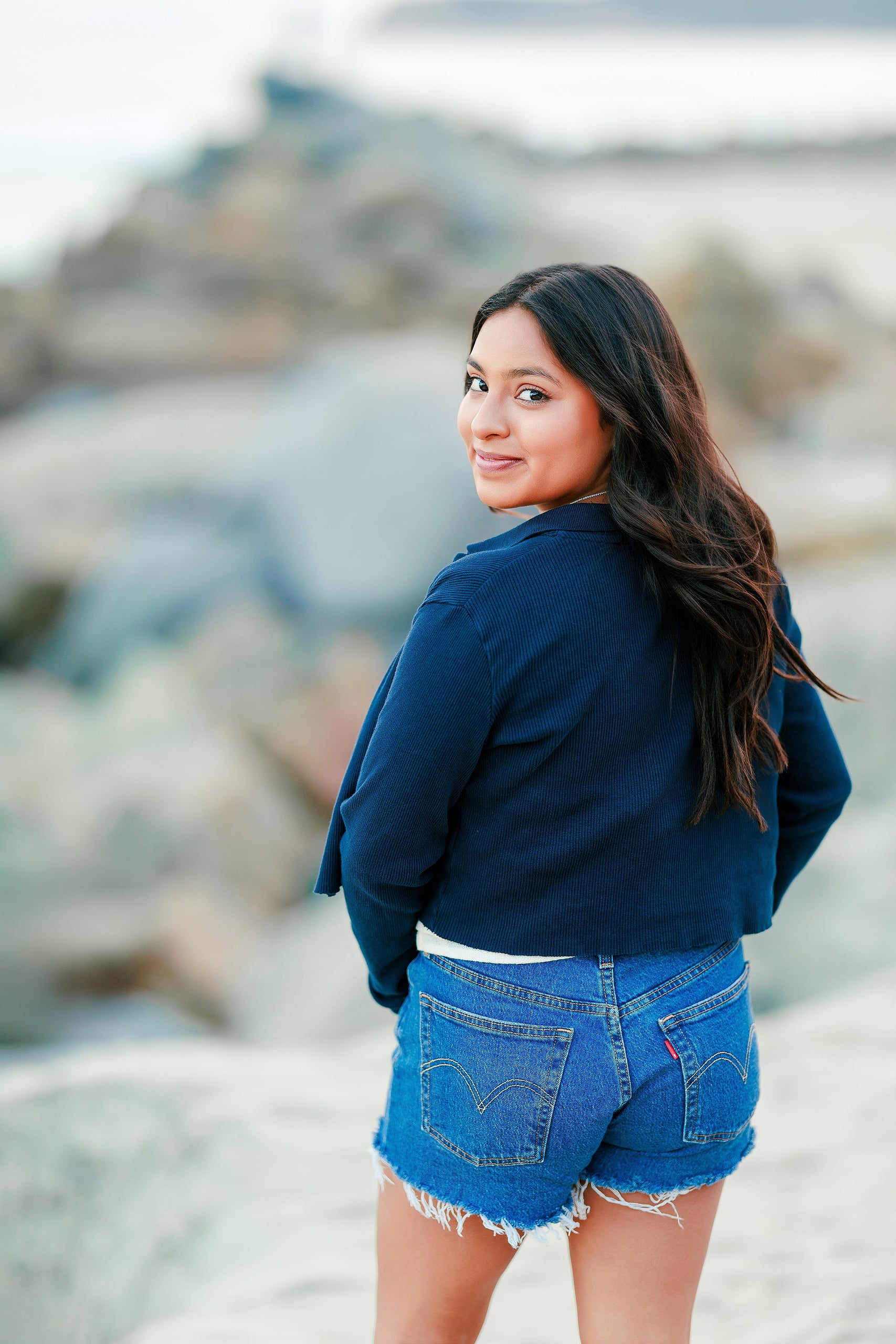 Evanna, Atalia, and Erleen’s Senior Session on Coronado — 20 Senior in navy cardigan and denim by ocean at Coronado beach