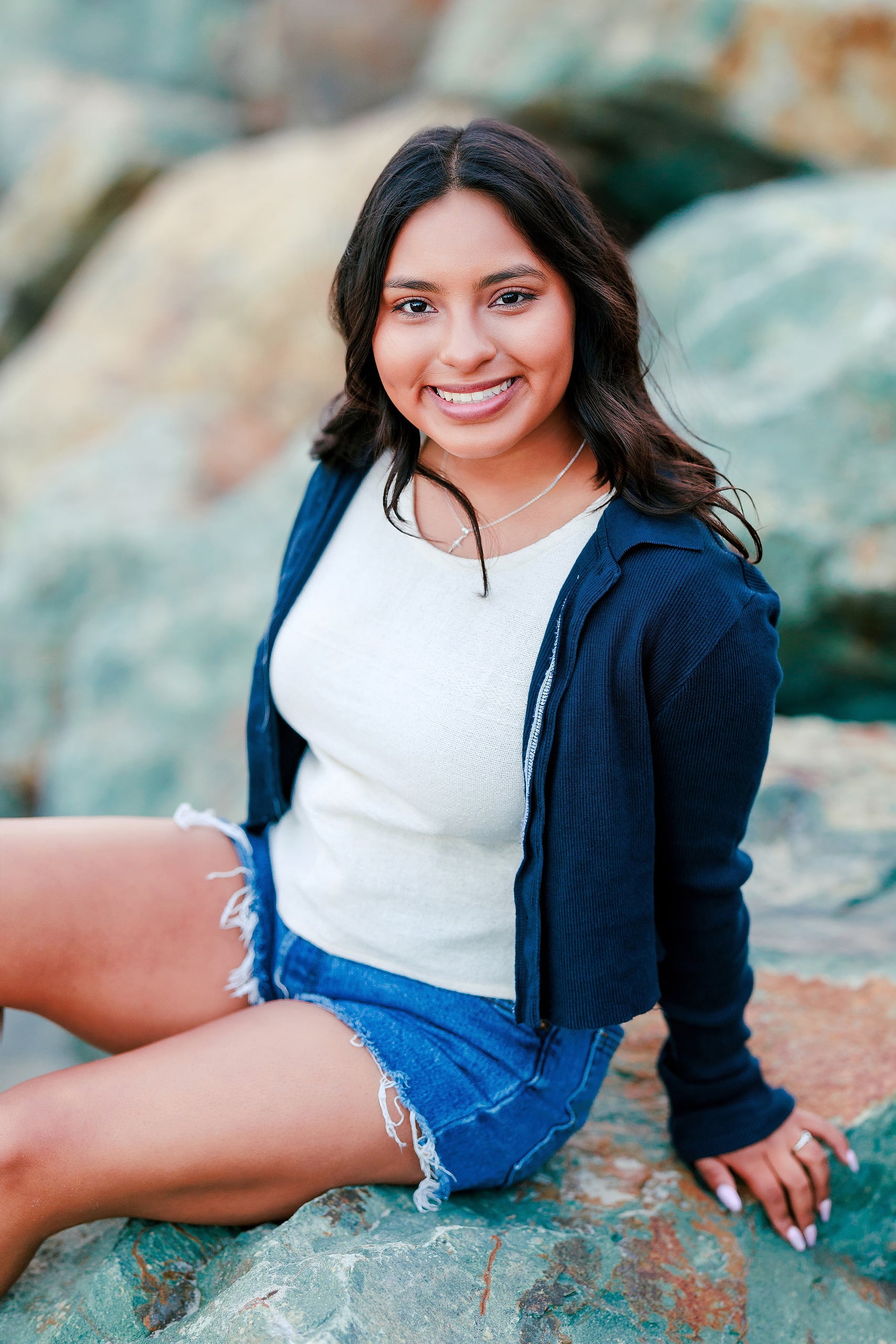 Evanna, Atalia, and Erleen’s Senior Session on Coronado — 24 Senior sitting on turquoise rocks by ocean at Coronado beach
