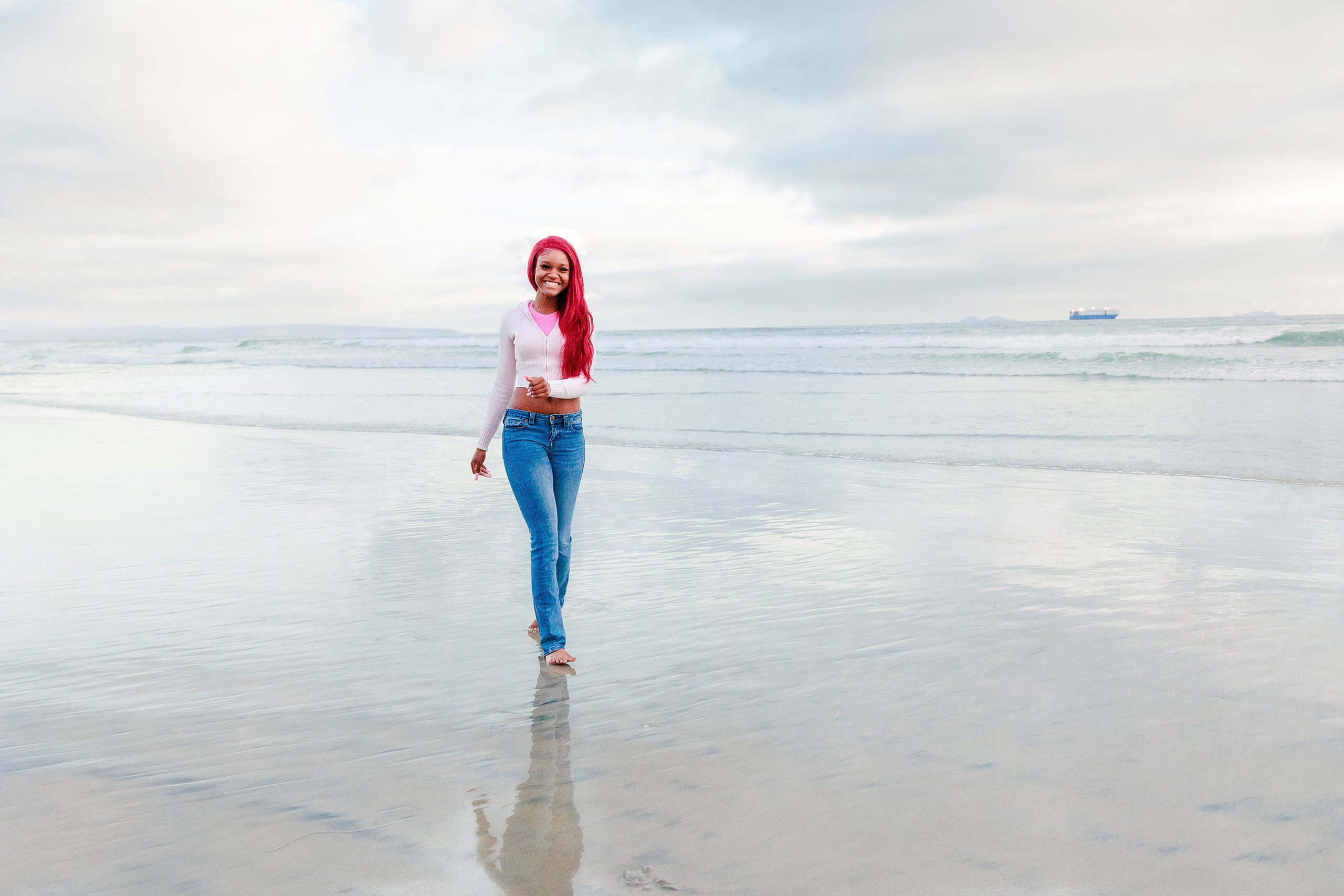 Evanna, Atalia, and Erleen’s Senior Session on Coronado — 27 Senior with pink hair walking alone on sand at Coronado beach