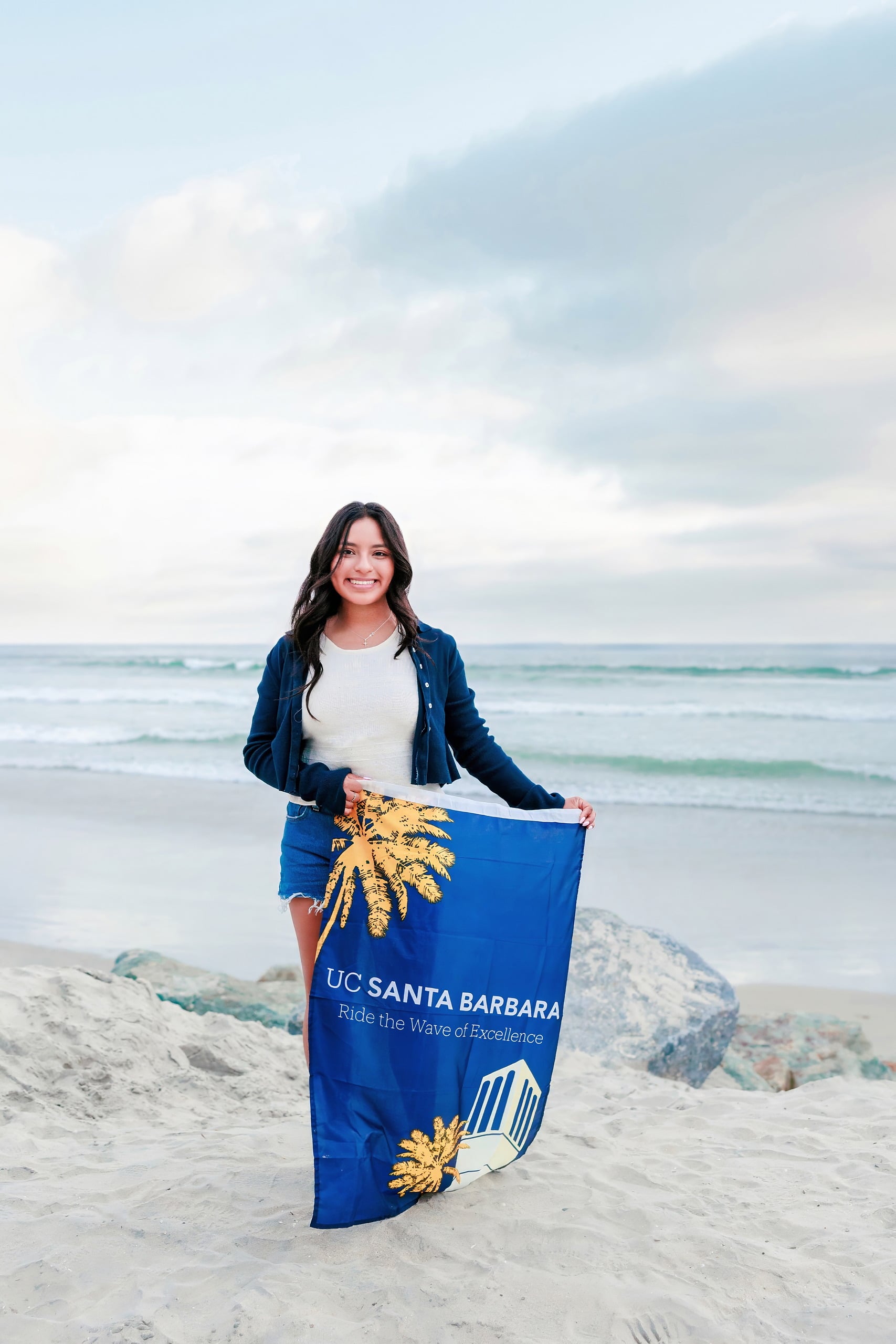 Evanna, Atalia, and Erleen’s Senior Session on Coronado — 34 Senior holding UC Santa Barbara flag on sand at Coronado beach