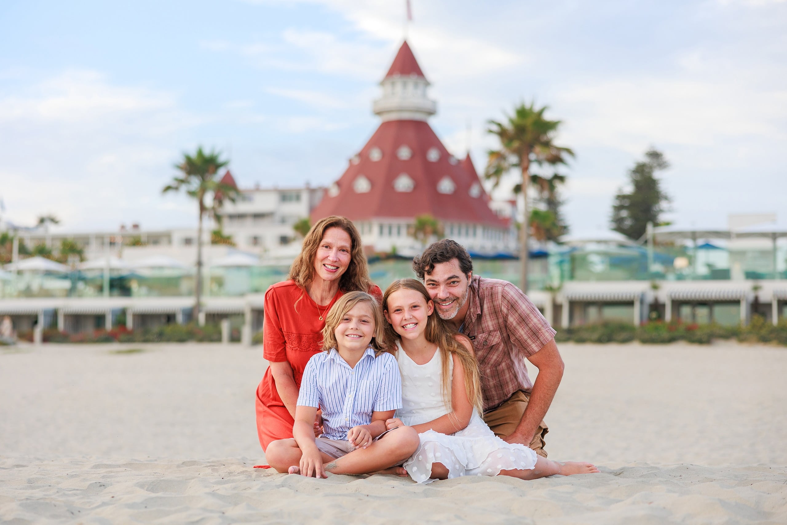 Extended Family Photography Hotel Del Coronado — 02 Two adults and three children gather on beach with Hotel del Coronado beyond