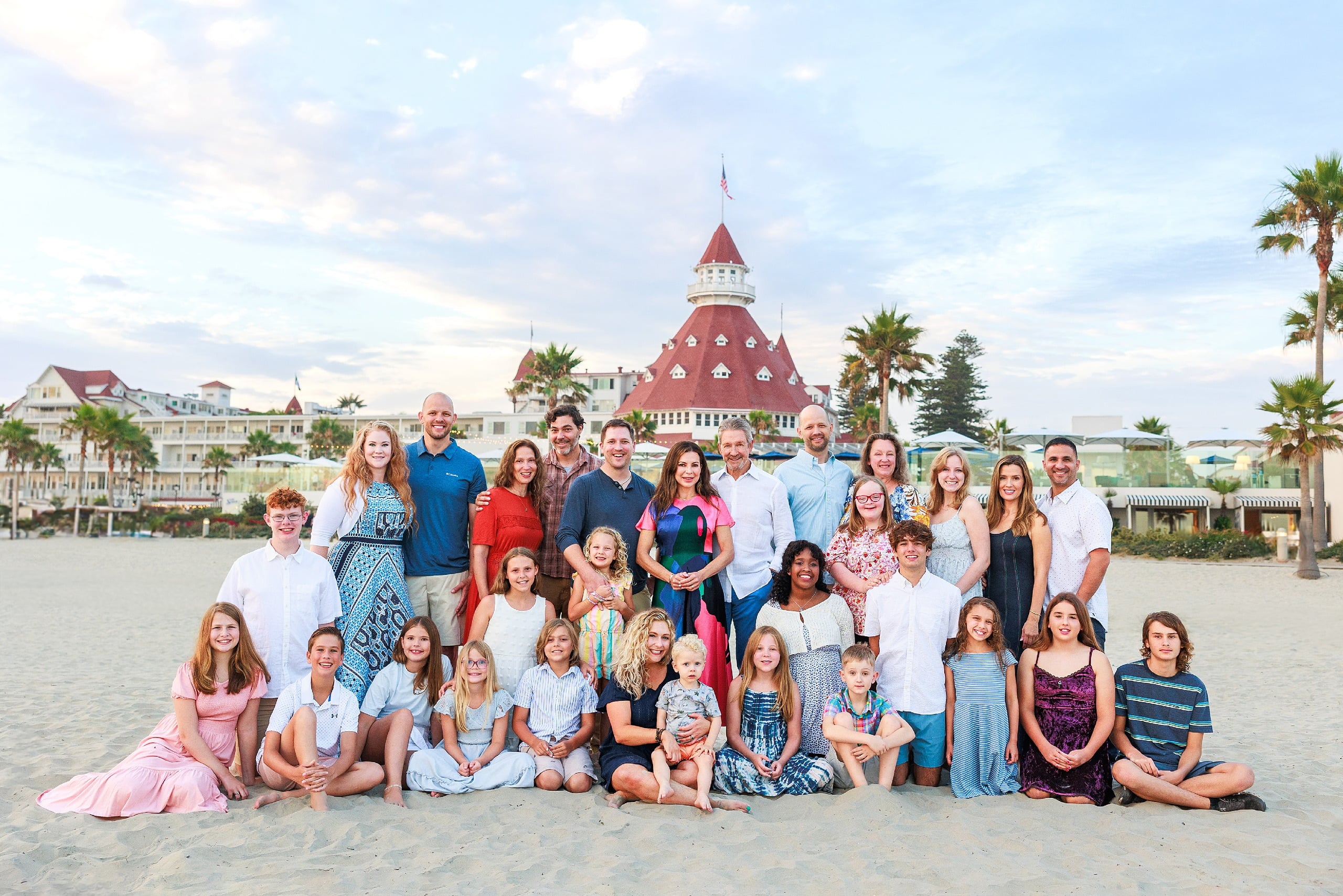 Extended Family Photography Hotel Del Coronado — 07 Large extended family sits and stands clustered together on sandy beach