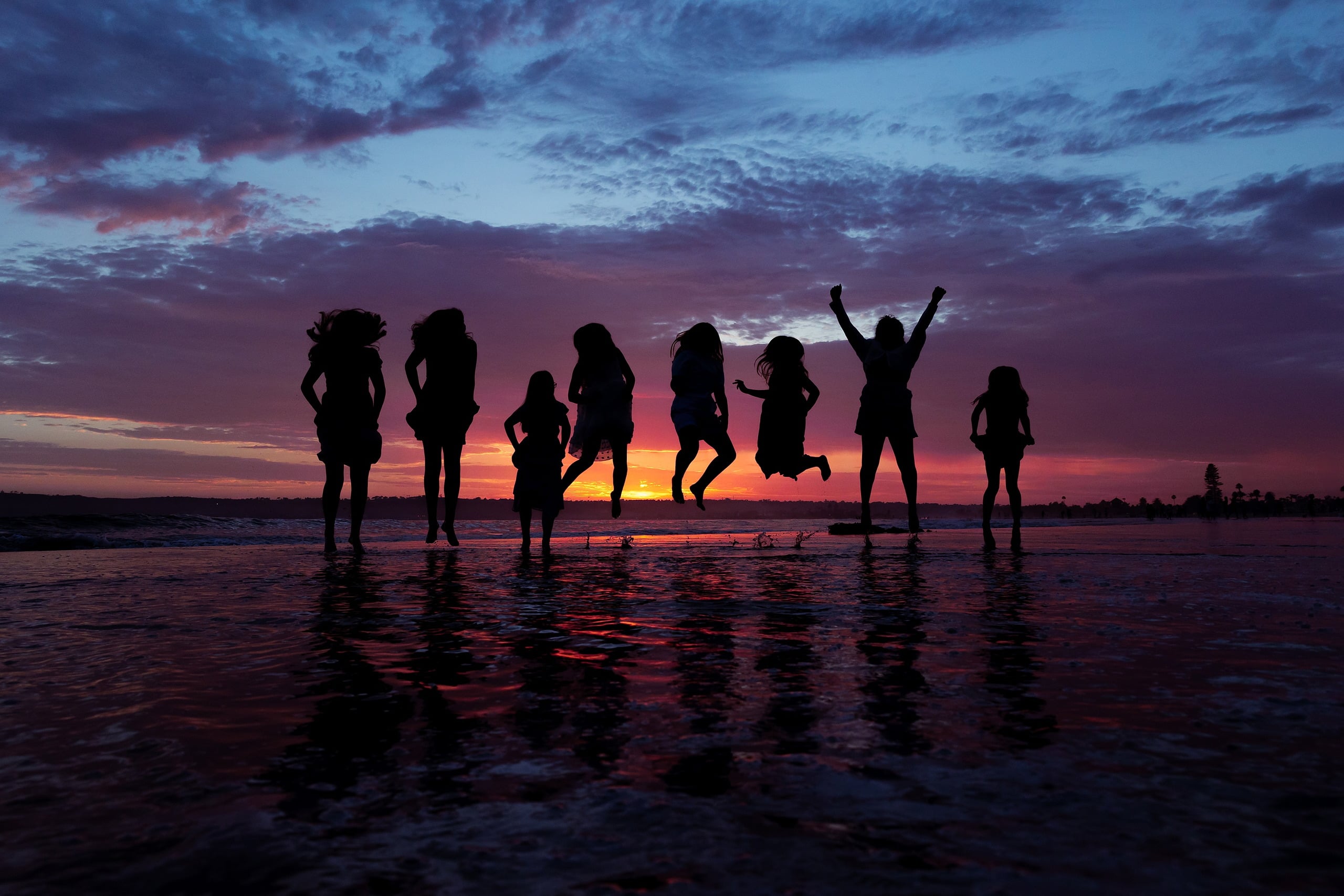 Extended Family Photography Hotel Del Coronado — 15 Silhouetted family group stands on wet sand during brilliant sunset