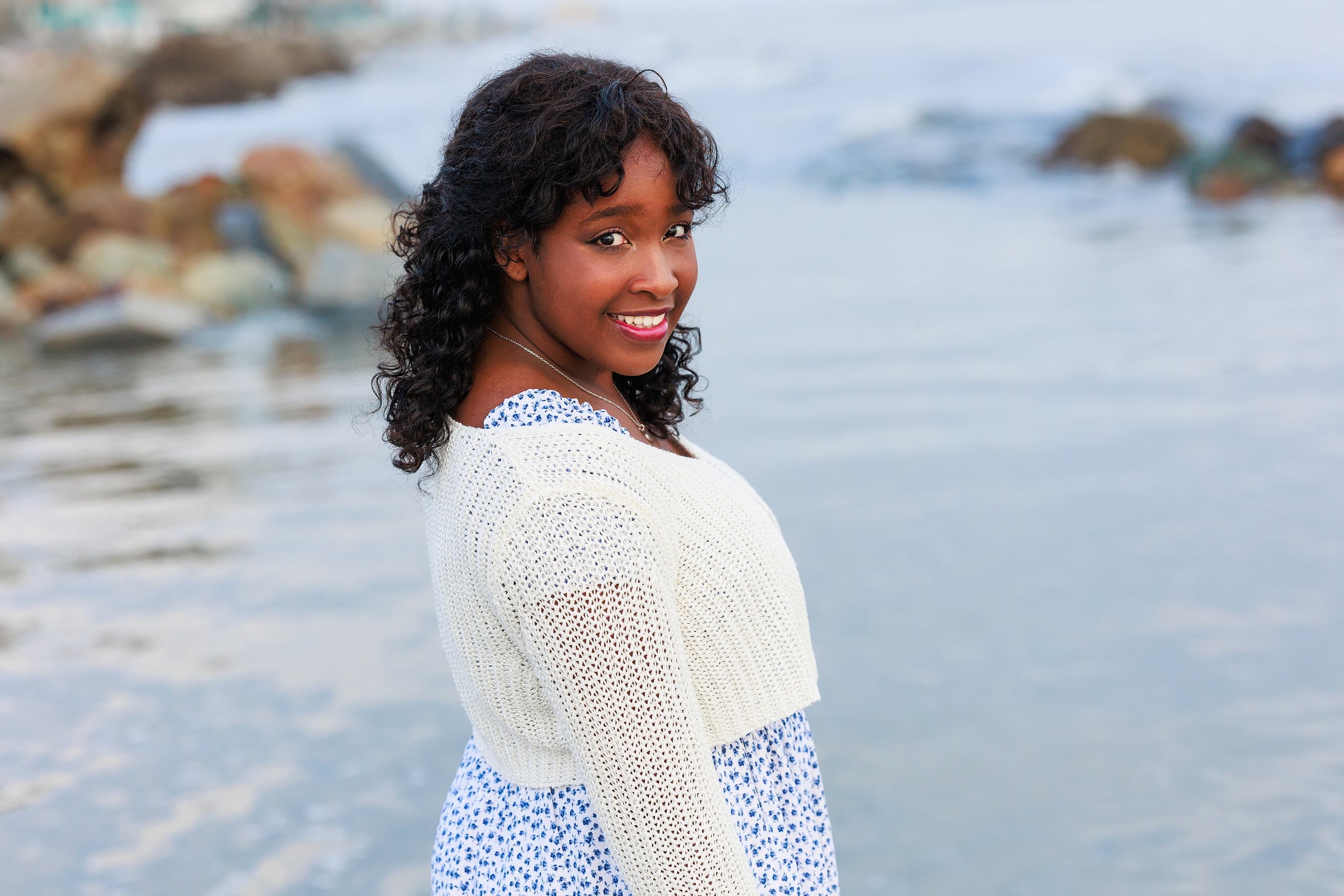 Extended Family Photography Hotel Del Coronado — 16 Woman looks back over her shoulder while standing on rocky Coronado beach