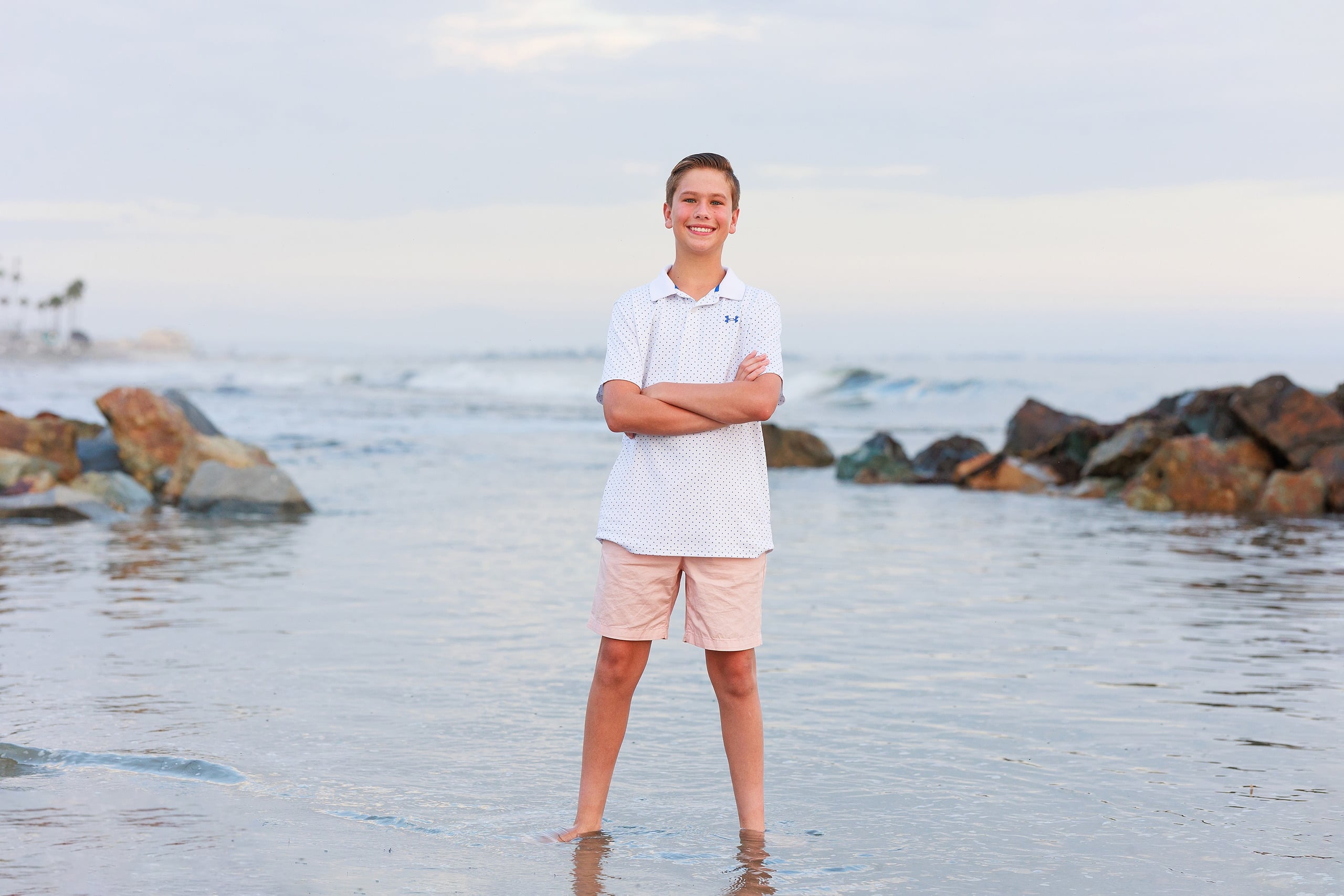 Extended Family Photography Hotel Del Coronado — 17 Teen boy wades confidently in shallow ocean water with arms crossed