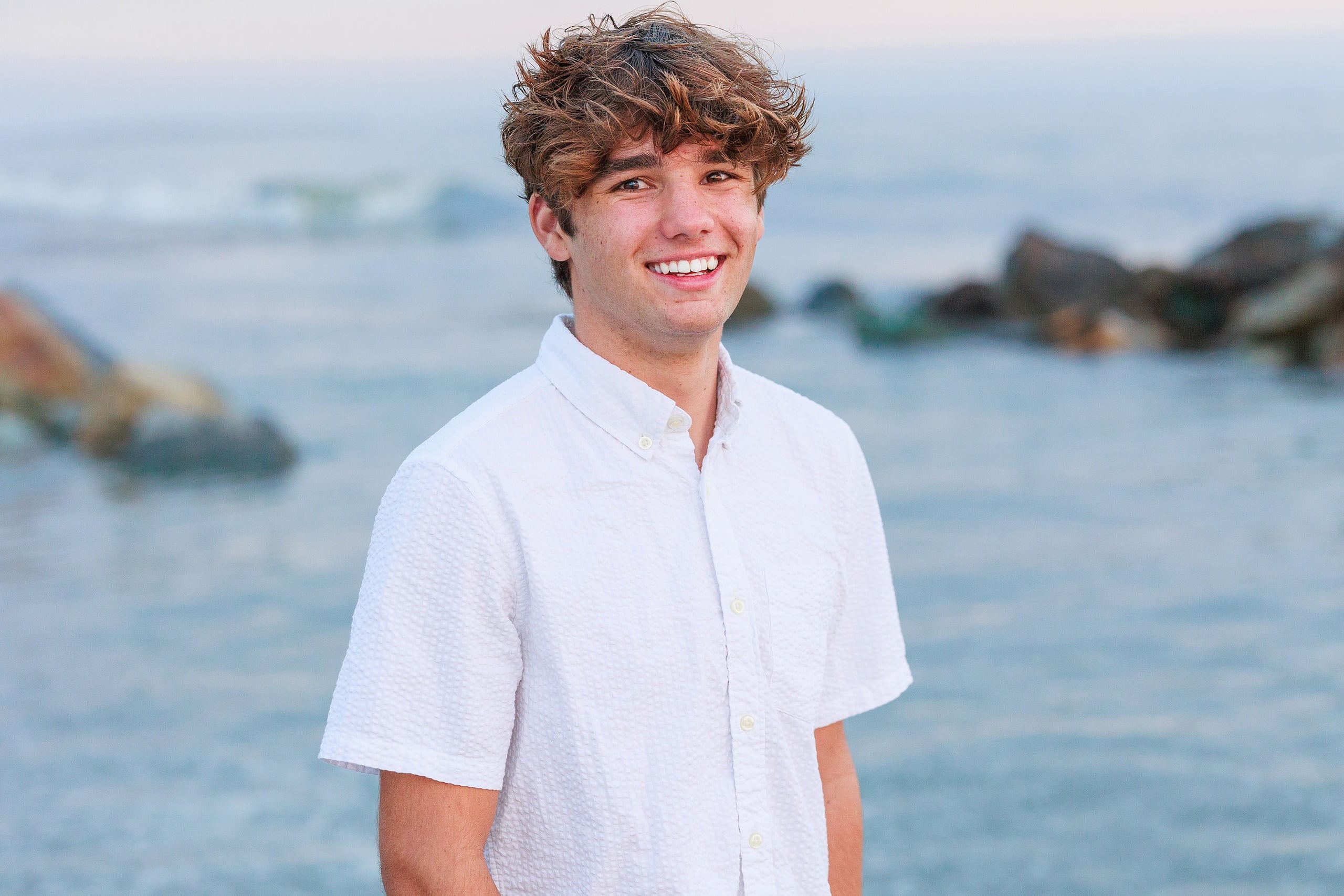 Extended Family Photography Hotel Del Coronado — 20 Teen boy in white shirt stands in shallow water, contemplative expression