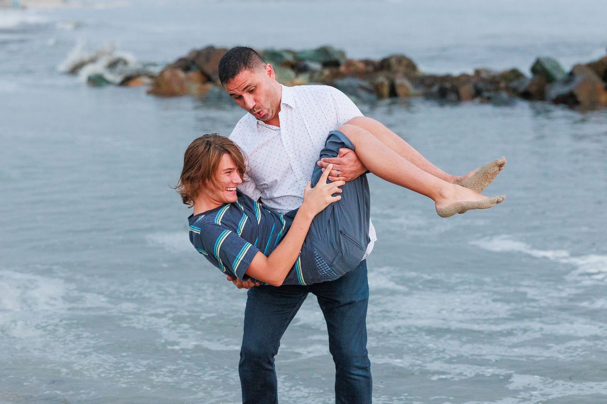 Extended Family Photography Hotel Del Coronado — 22 Man playfully carries child above his shoulder in shallow ocean