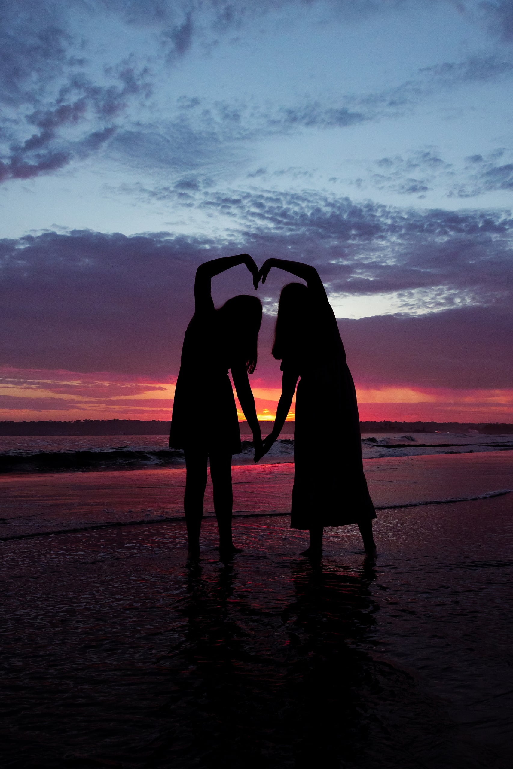 Extended Family Photography Hotel Del Coronado — 25 Two girls create a heart shape silhouetted against vibrant sunset sky