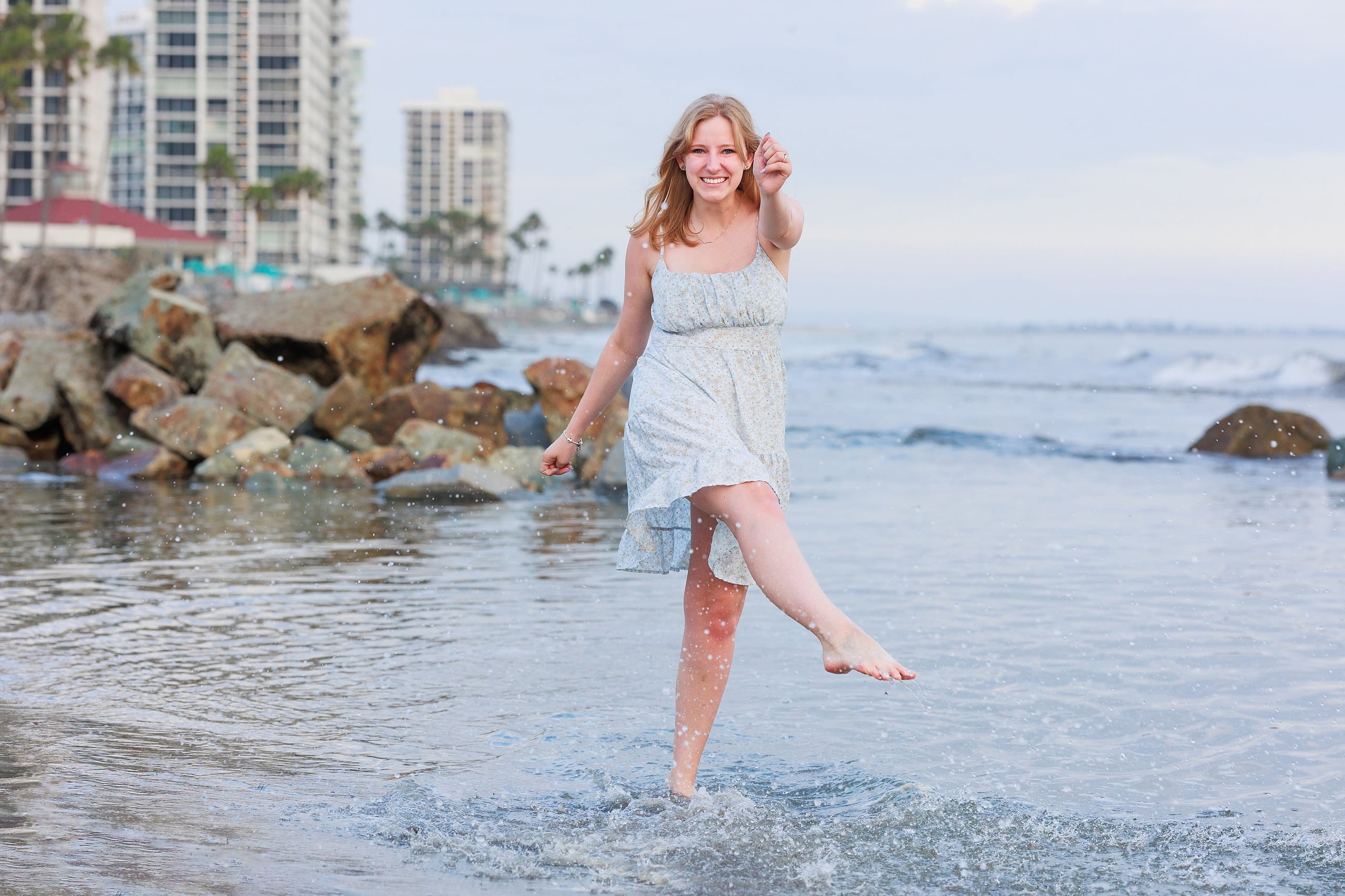 Extended Family Photography Hotel Del Coronado — 27 Teen girl in light dress wades in shallow water, beaming at camera