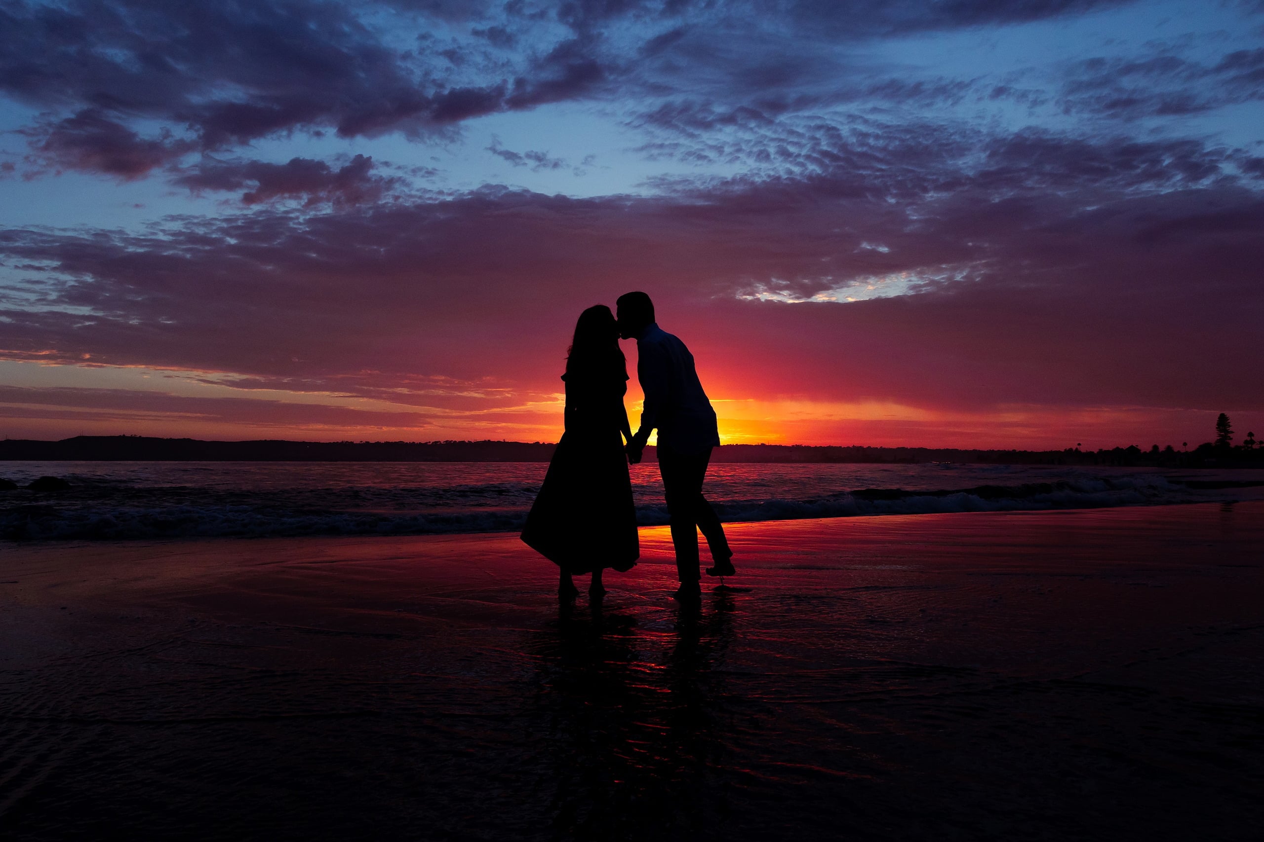 Extended Family Photography Hotel Del Coronado — 29 Couple silhouetted standing together in shallow water against dramatic sunset