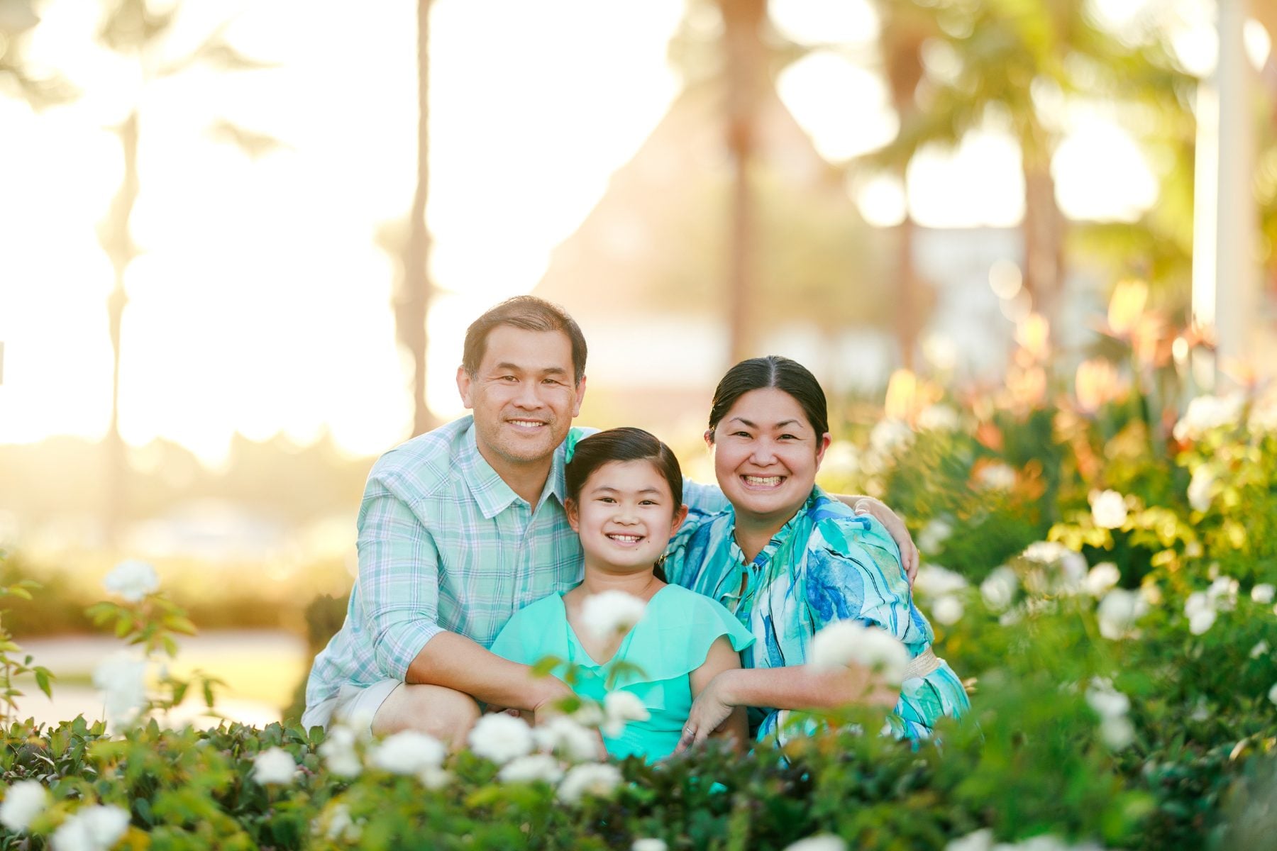 Family of three crouches among white roses at Hotel Del Coronado