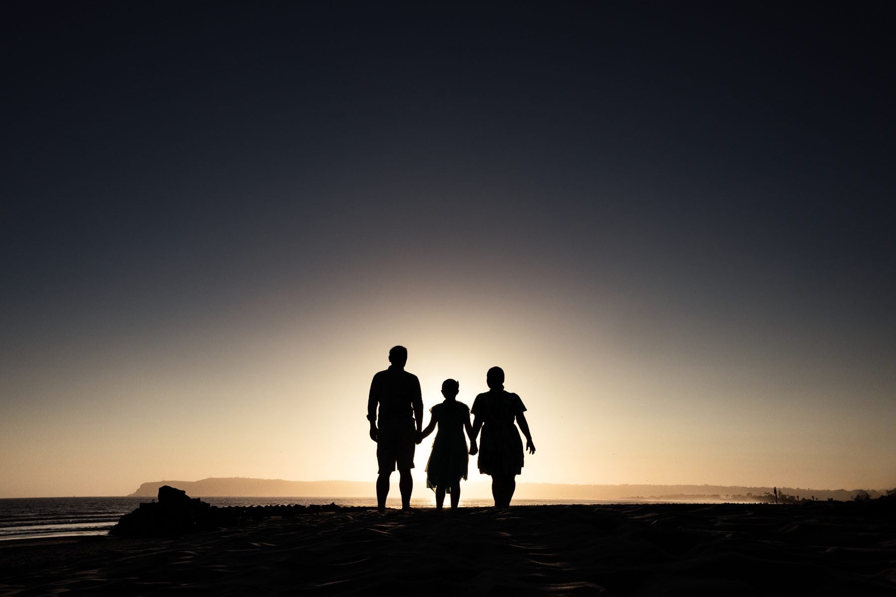 Silhouette of family walking hand in hand at Coronado Beach sunset