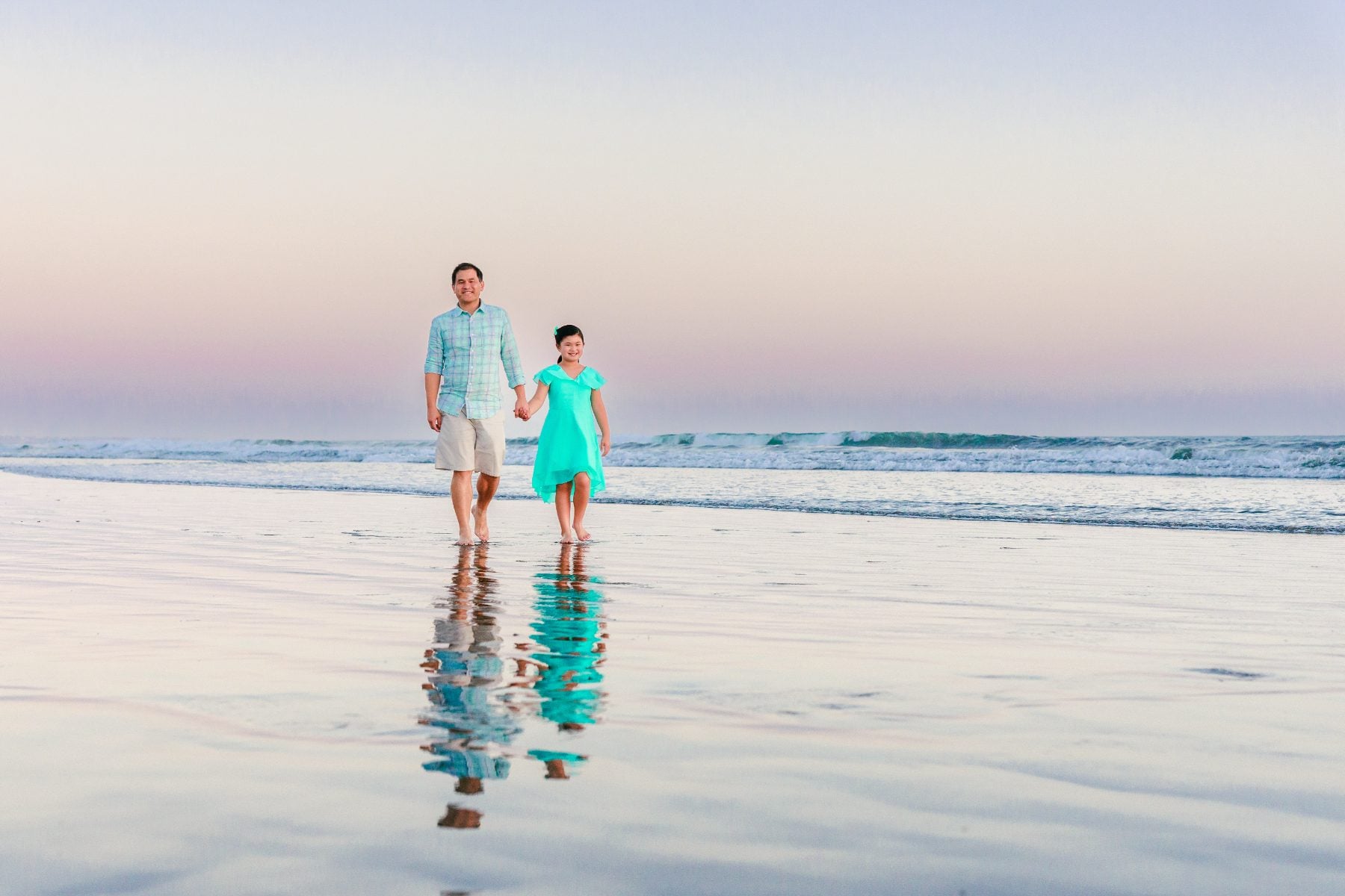 Father and daughter walking hand in hand on Coronado Beach shoreline