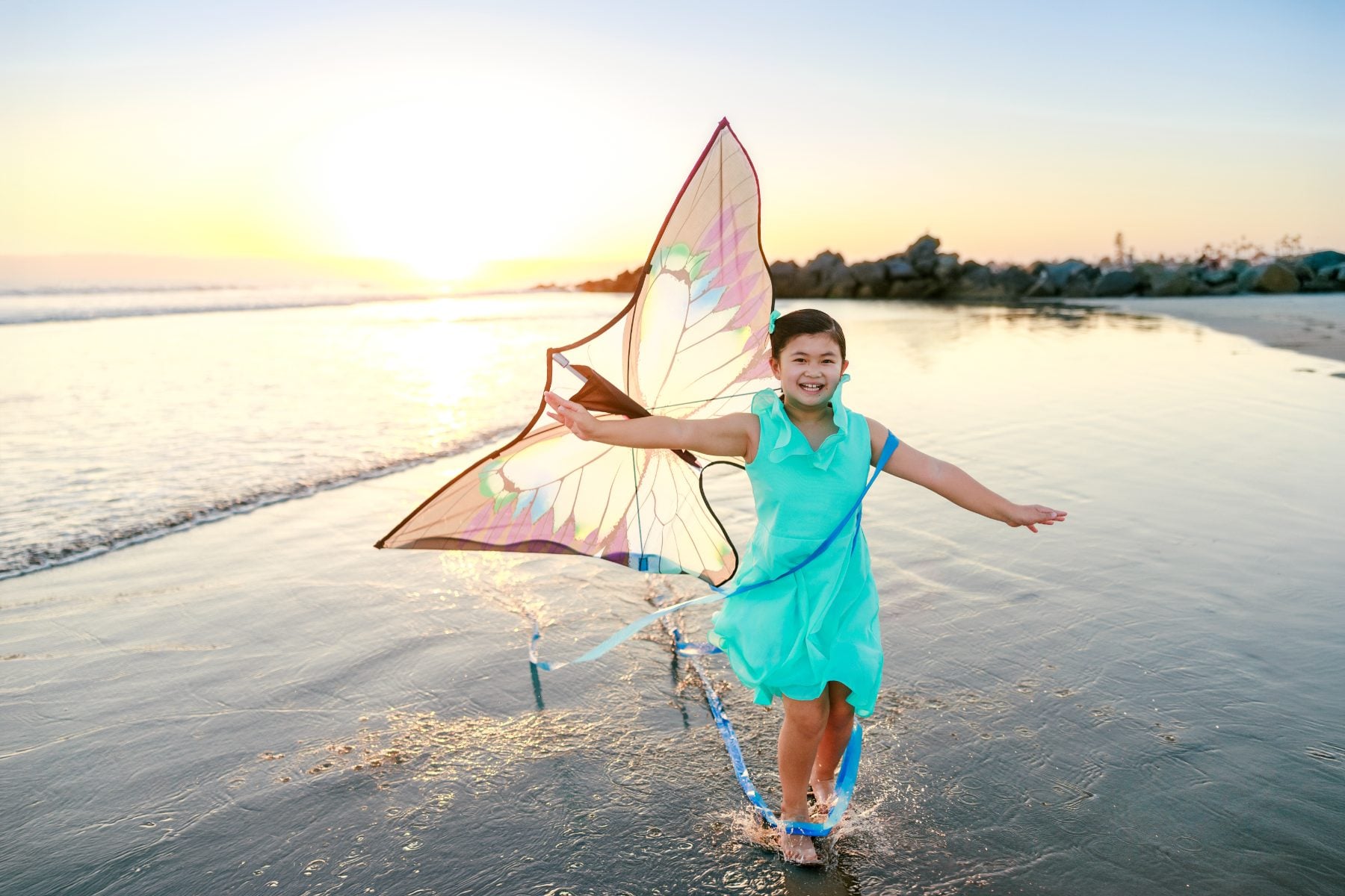 Girl smiling while flying a butterfly kite on Coronado Beach