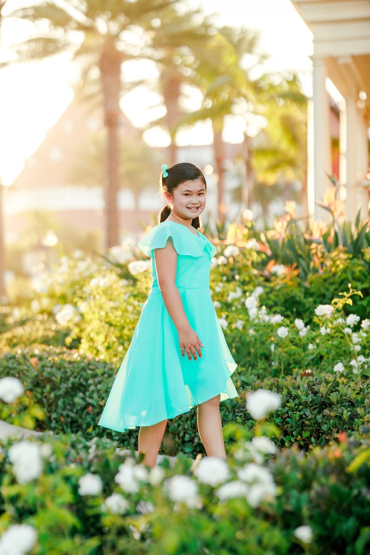 Girl in turquoise dress strolls through Hotel Del Coronado garden