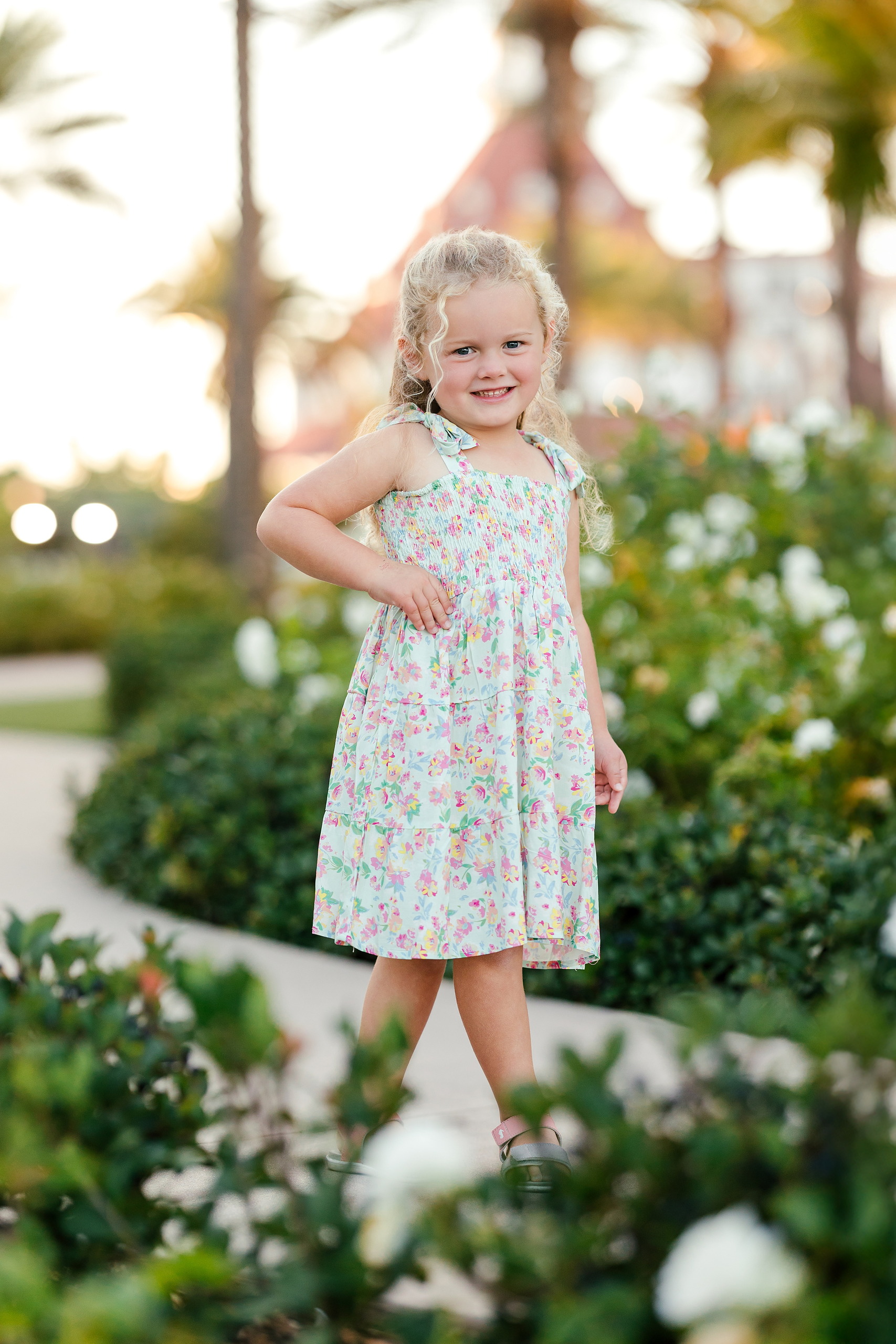 Hotel del Coronado Family Photos — 04 Mabel standing and smiling in floral dress at Hotel del Coronado garden