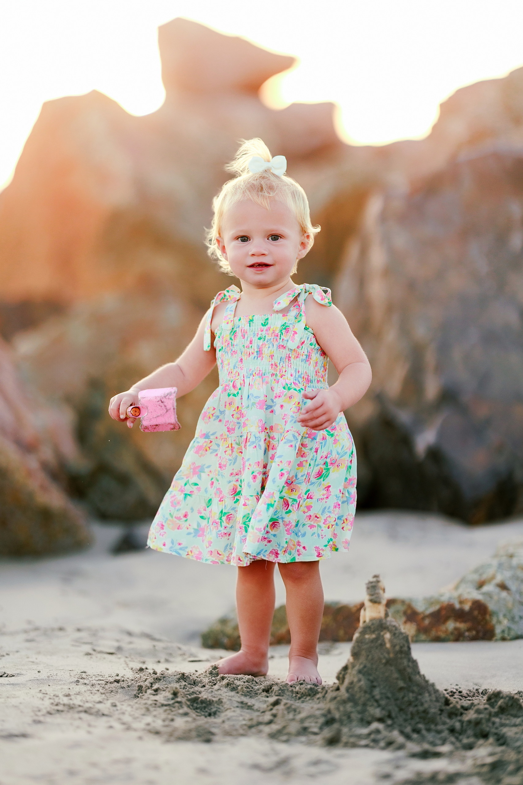 Hotel del Coronado Family Photos — 11 Poppy standing with hands at sides on Coronado beach holding pink shovel