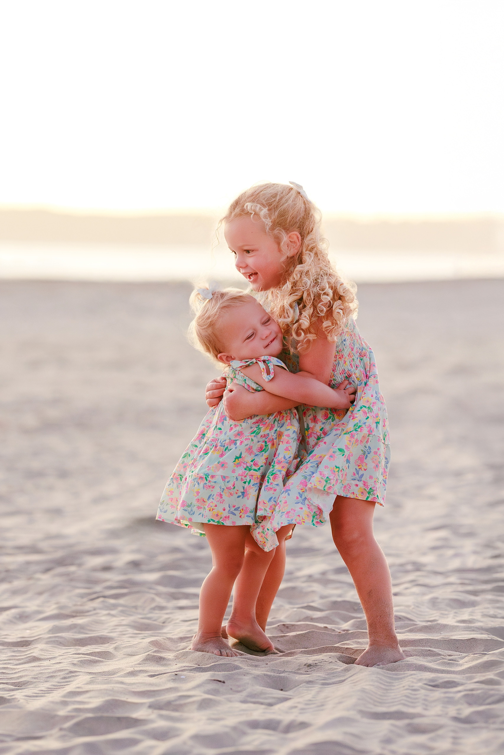 Hotel del Coronado Family Photos — 24 Mabel carrying Poppy in the sand at Coronado beach at golden hour