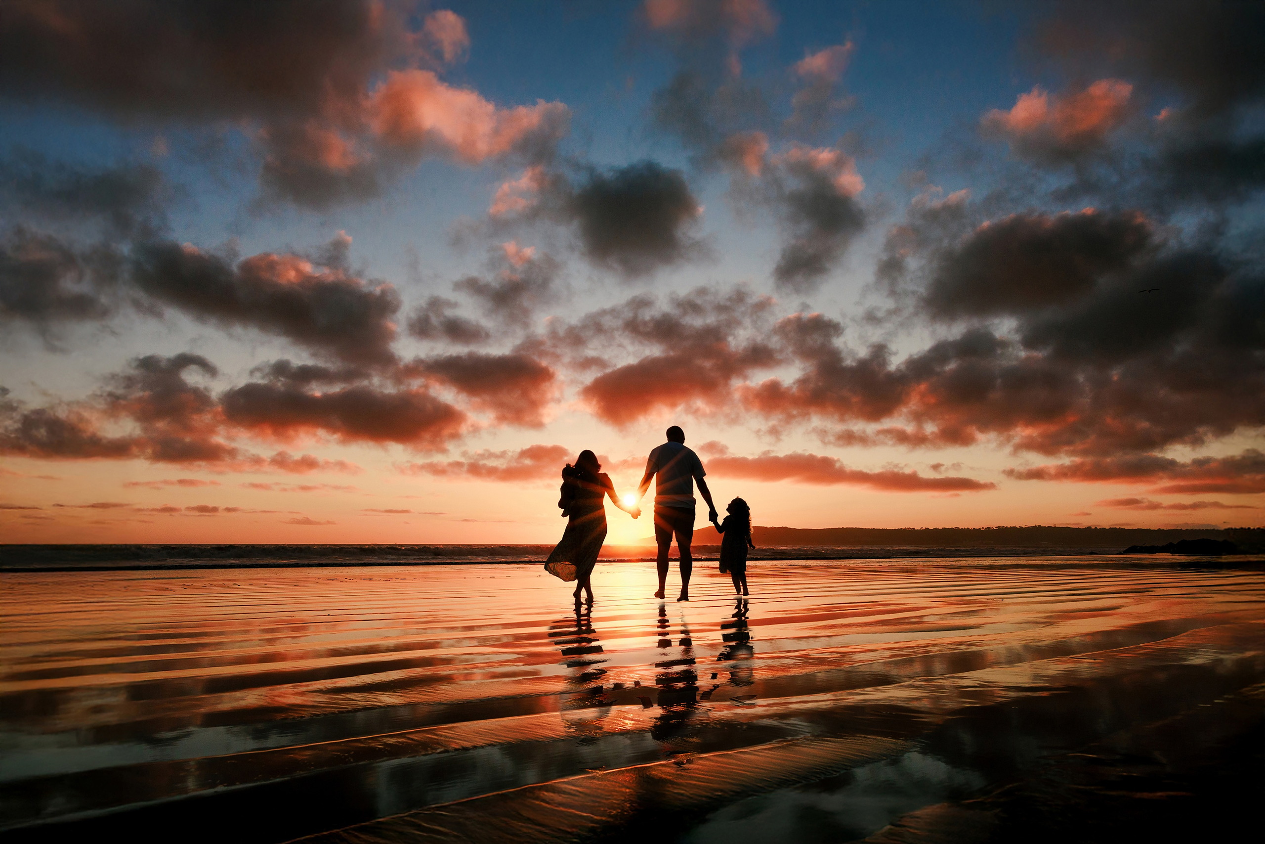 Hotel del Coronado Family Photos — 25 Family silhouetted against a dramatic sunset sky on Coronado beach