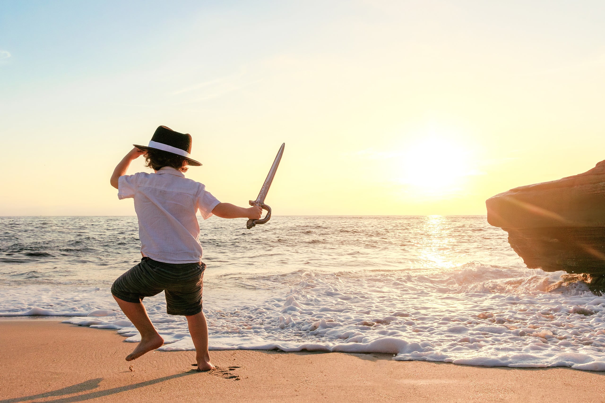 La Jolla Family Photography — 02 Child wielding pirate sword on beach at golden hour with waves in background