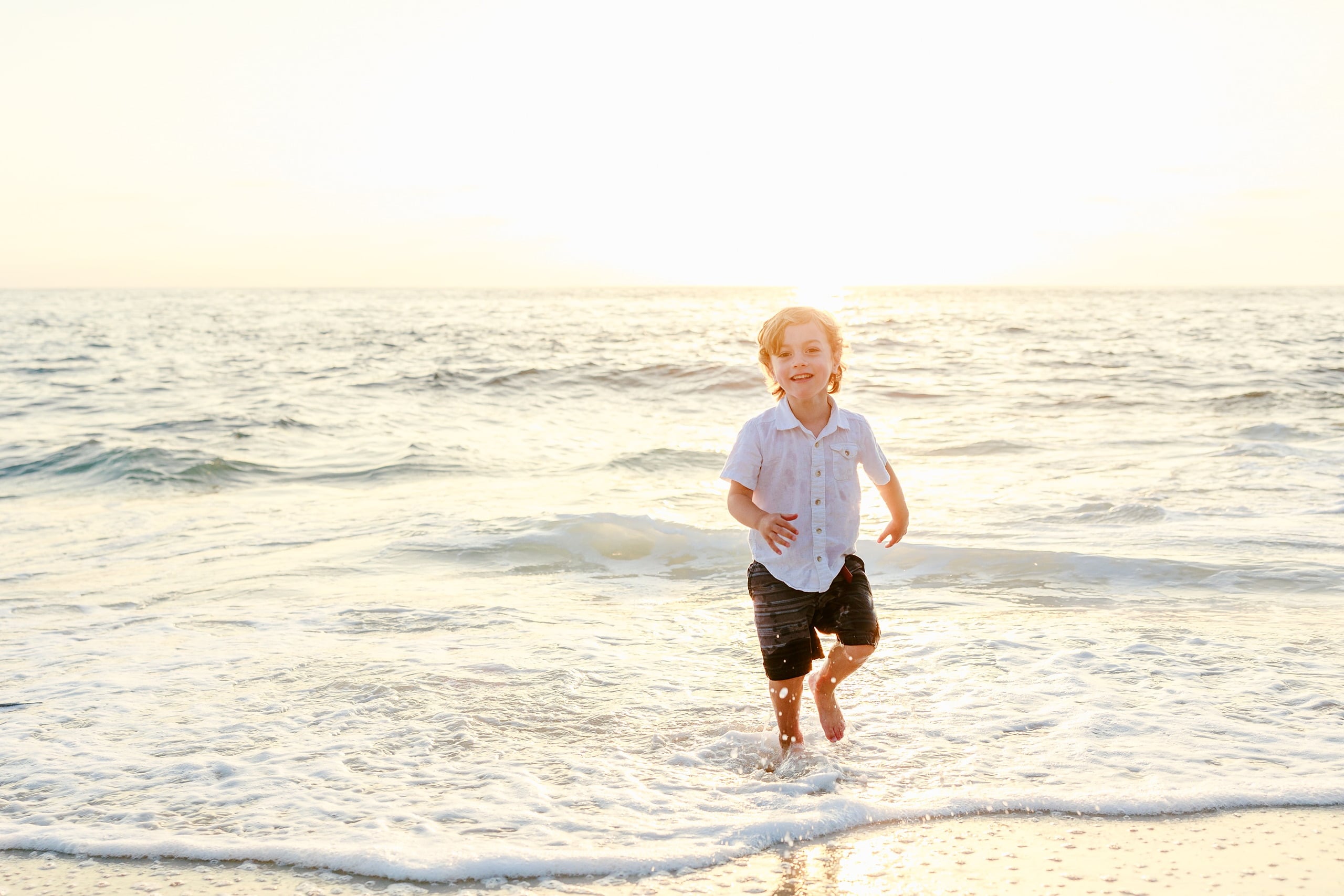 La Jolla Family Photography — 08 Child in white shirt running through shallow water on beach