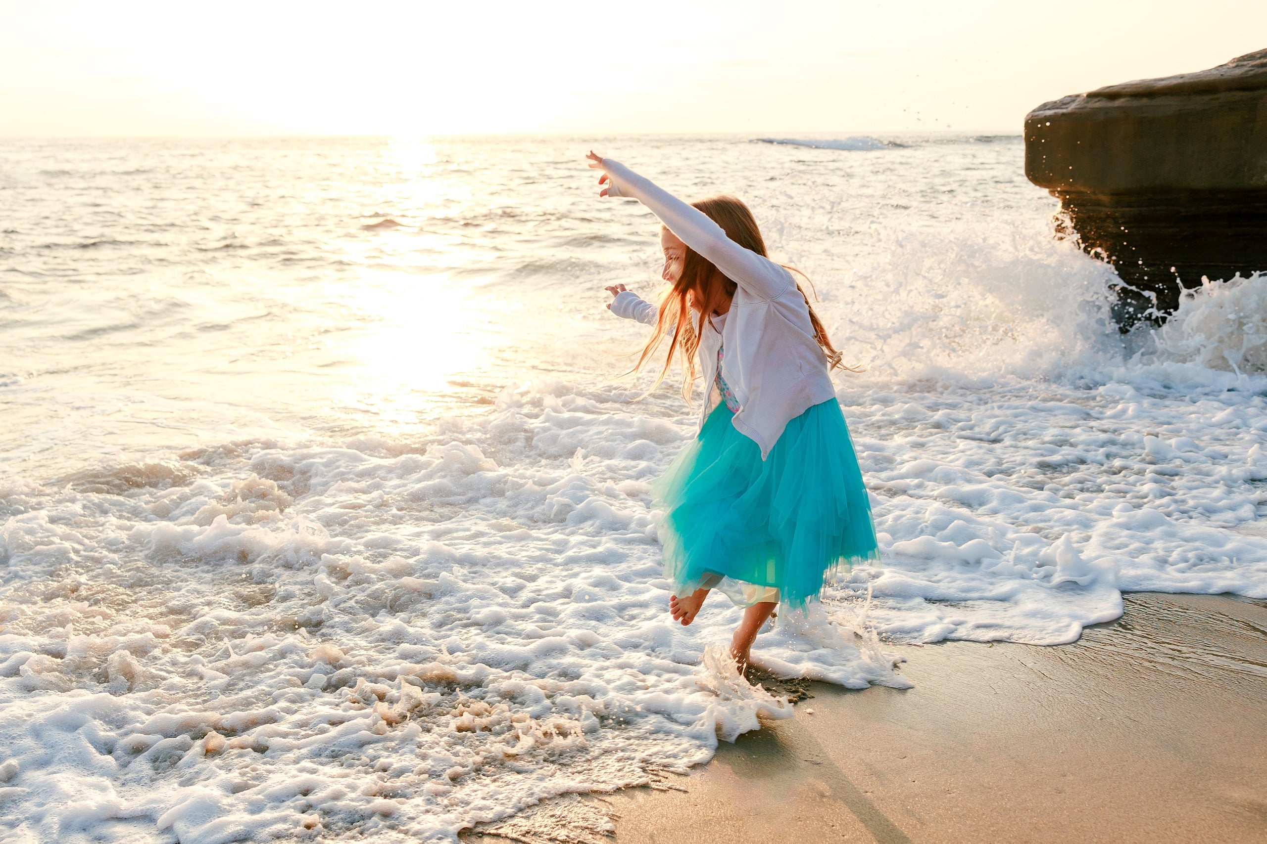 La Jolla Family Photography — 09 Child in turquoise tulle skirt spinning on beach with arms outstretched