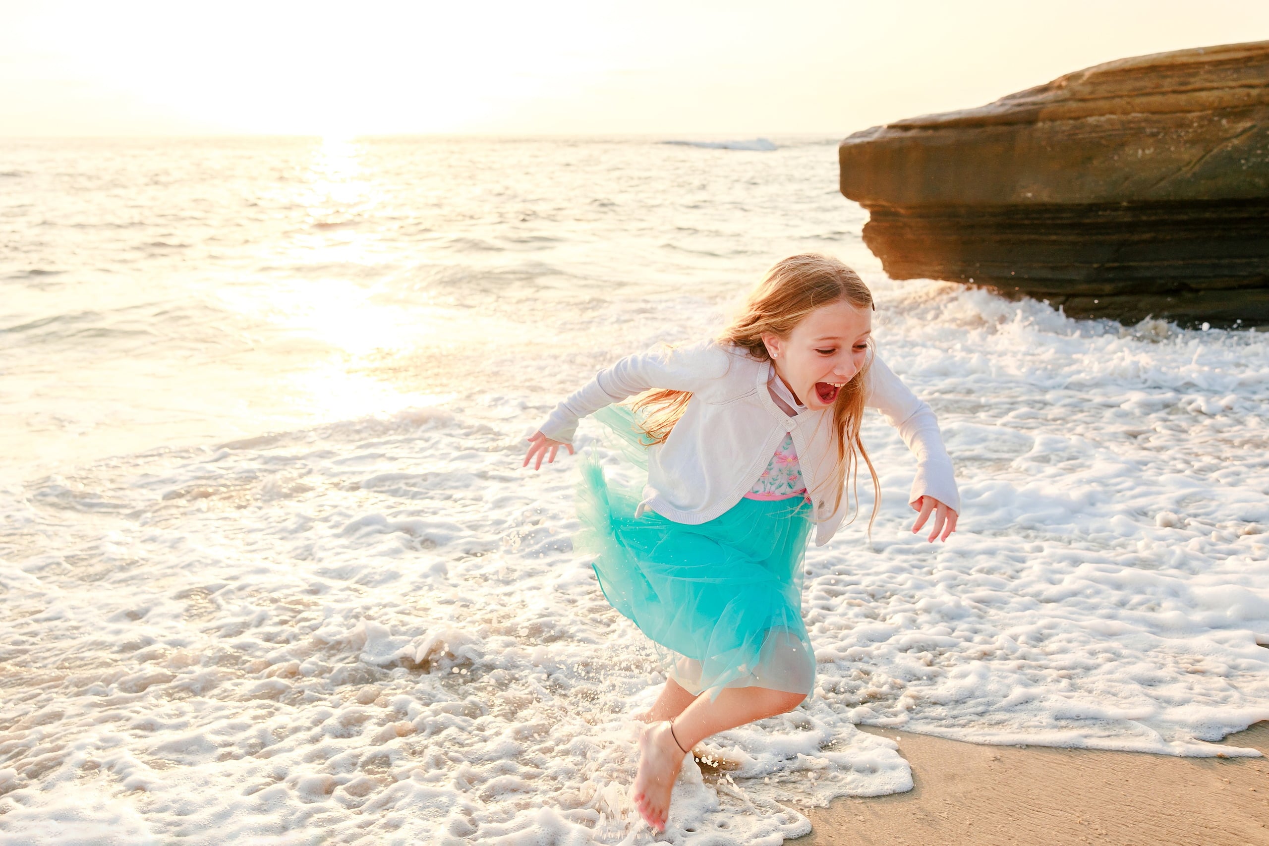 La Jolla Family Photography — 11 Child in turquoise tulle skirt splashing through waves on beach