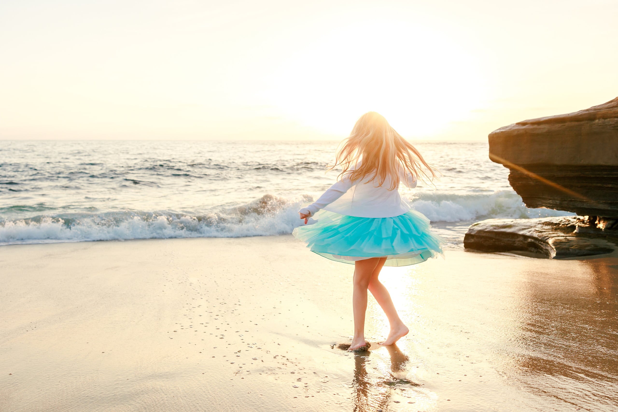 La Jolla Family Photography — 12 Child in turquoise skirt spinning with dress flying on beach