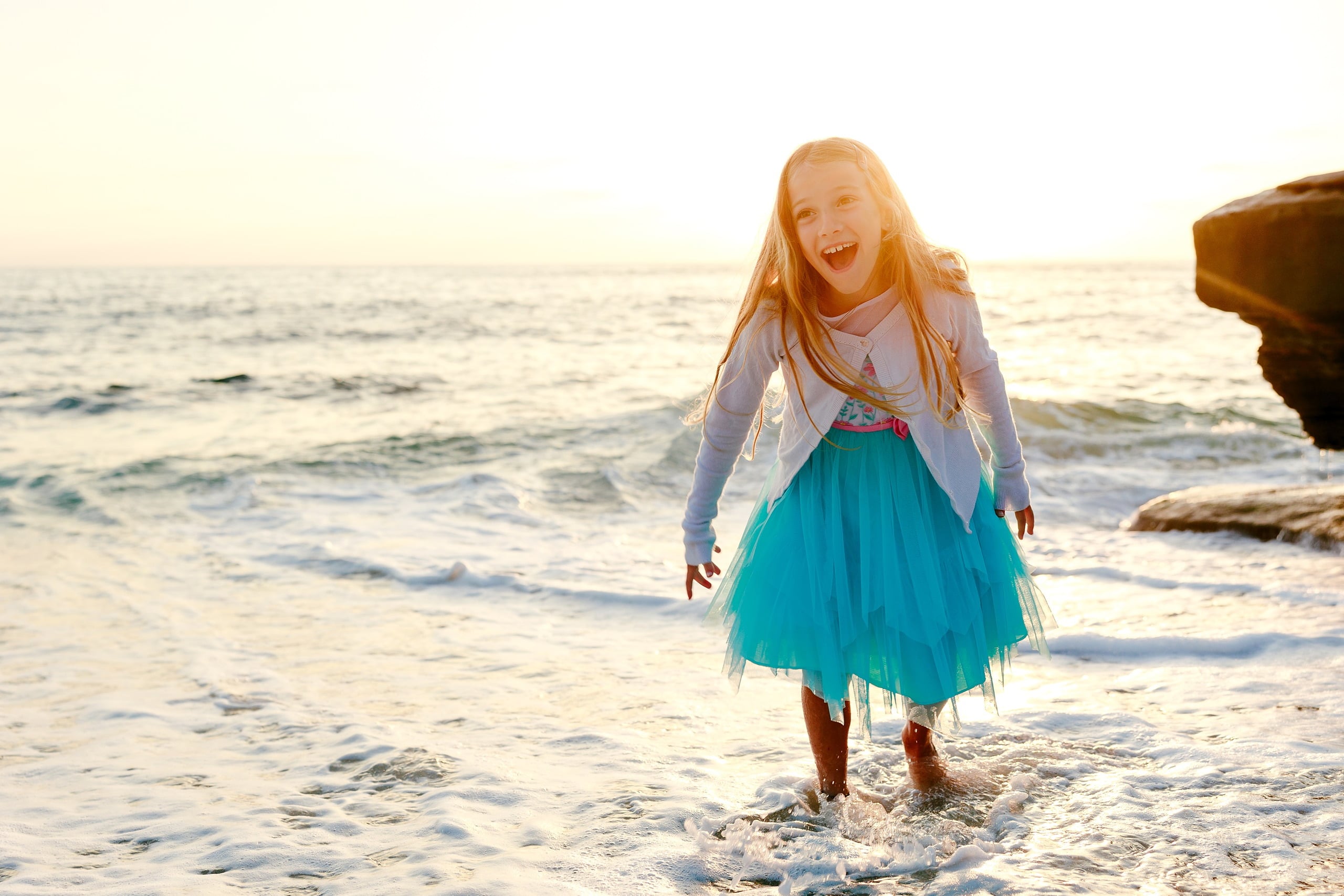 La Jolla Family Photography — 15 Child in turquoise skirt spinning in shallow water on beach