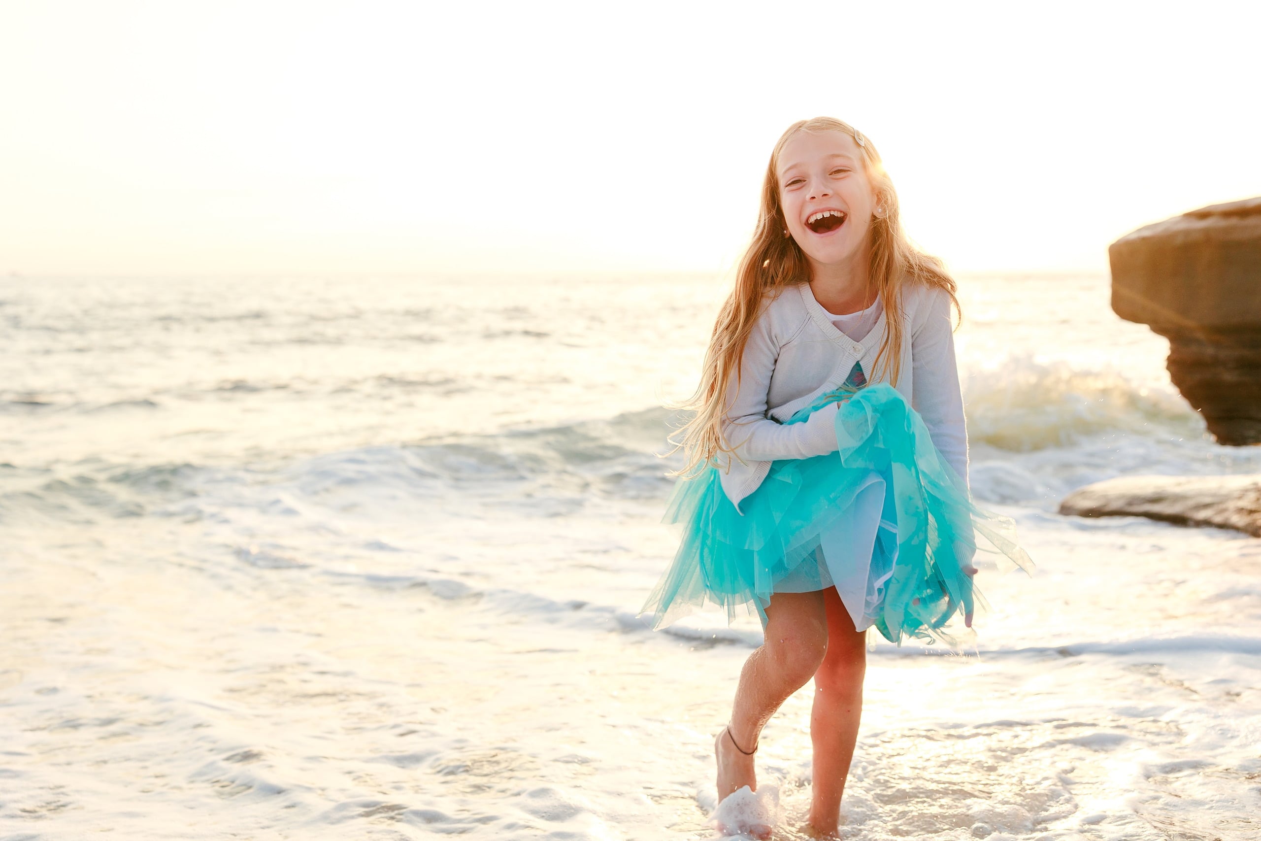 La Jolla Family Photography — 16 Child in white and turquoise skirt wading in water with arms outstretched
