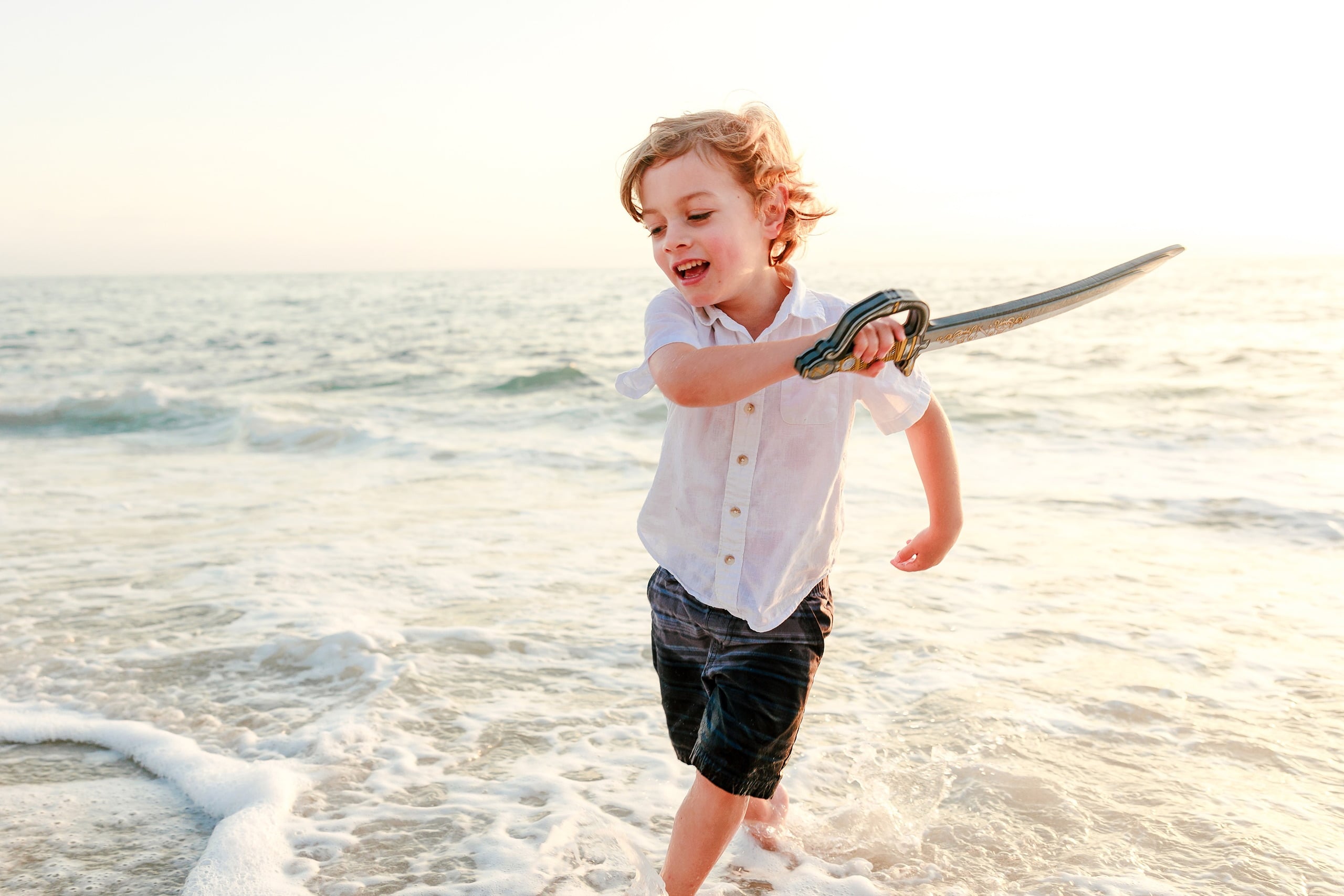 La Jolla Family Photography — 18 Child running with pirate sword held horizontally on beach