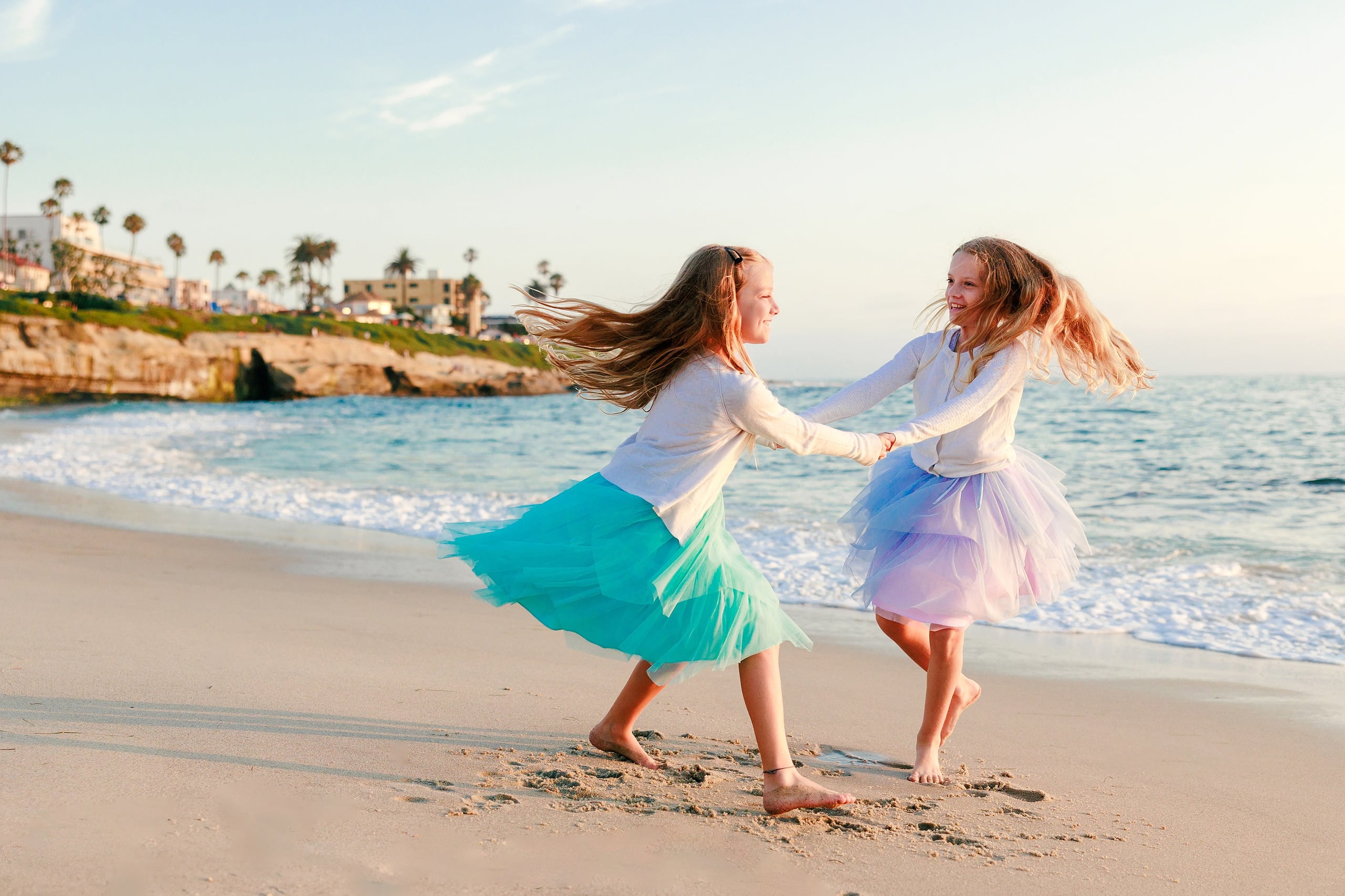 La Jolla Family Photography — 23 Two children holding hands spinning on beach with hair flying