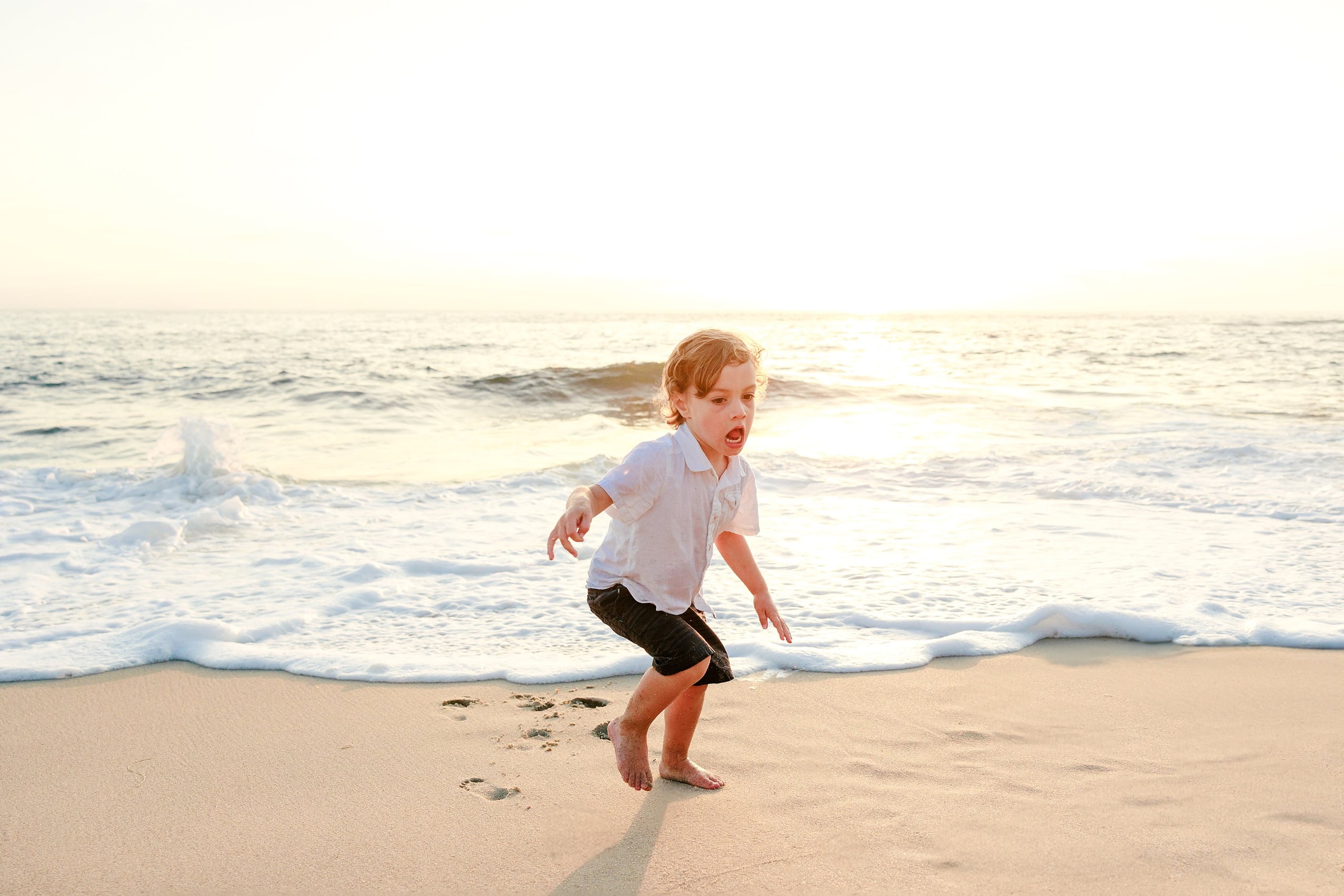 La Jolla Family Photography — 32 Toddler in white shirt running through shallow water on beach