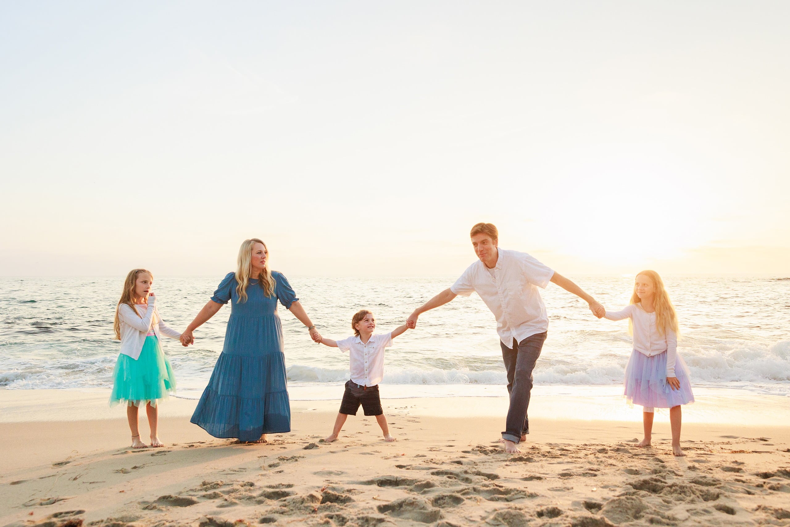 La Jolla Family Photography — 35 Family of five holding hands on beach at golden hour with rocky outcrop visible